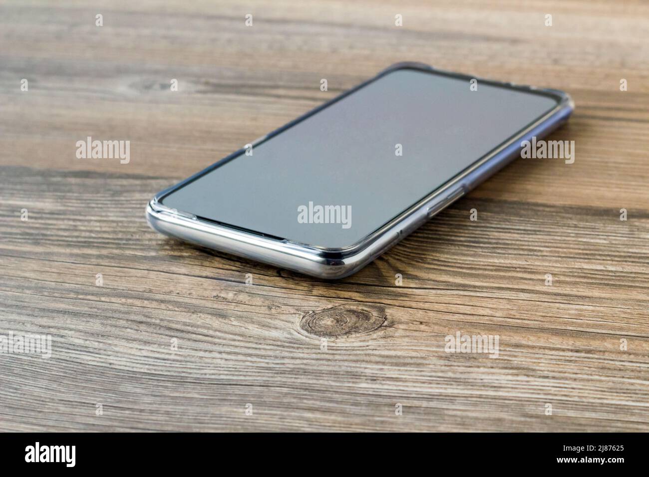 Smartphone con schermo bianco vuoto, adagiato su una superficie di legno con spazio per la copia. Foto Stock
