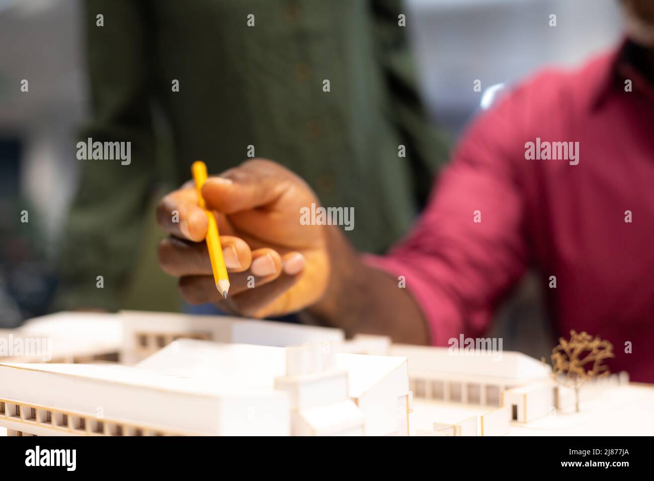 Architetto afroamericano che punta la matita al modello di architettura con il collega sul posto di lavoro Foto Stock