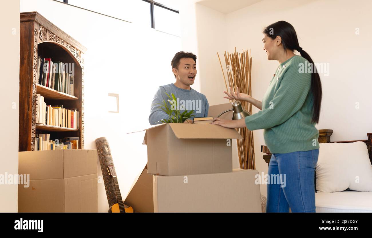 Eccitato giovane coppia asiatica unboxing in nuovo appartamento Foto Stock