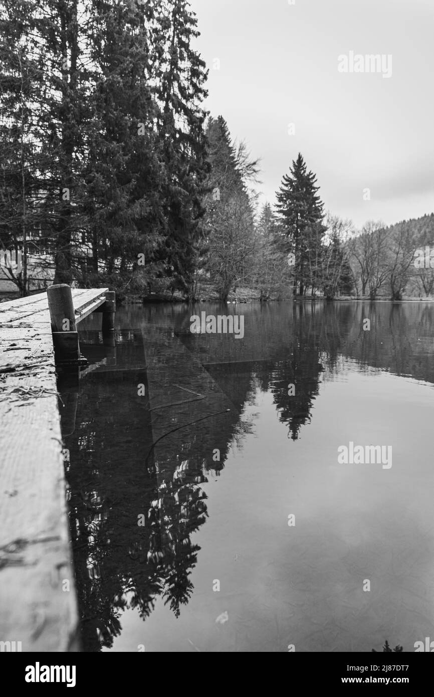 in questo tranquillo lago, una lunga passerella in legno conduce al centro. Gli alberi si riflettono nell'acqua Foto Stock