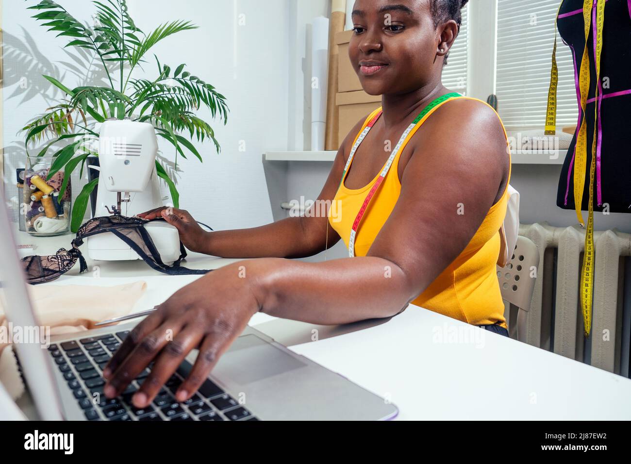 donna fashion designer con afro pigtail dreadlocks che lavora sul suo atelier casa Foto Stock