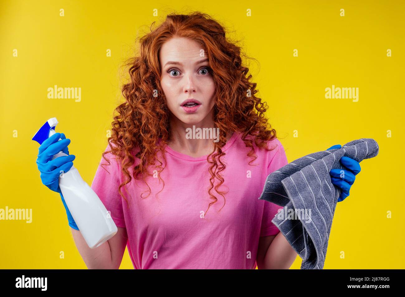 carino rosso capelli afro ricci zenzero donna lavaggio casa, studuo giallo parete Foto Stock