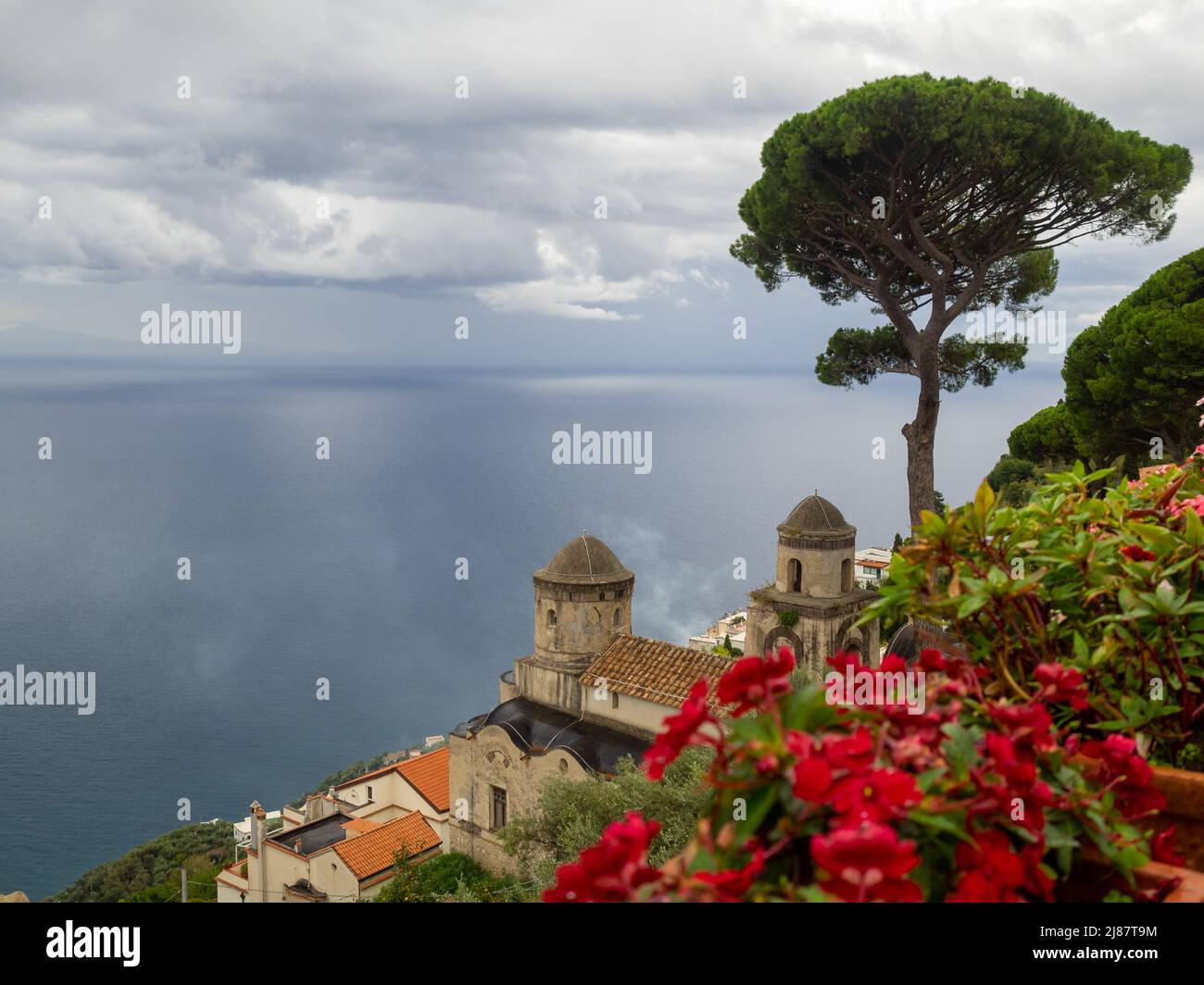 Fiori rossi nei giardini di Villa Rufolo con il mare di Amalfi sullo sfondo Foto Stock