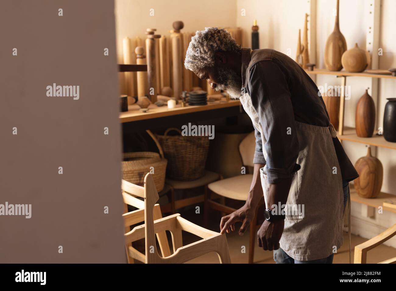 Vista laterale di falegname maturo afroamericano che fa mobili in officina Foto Stock