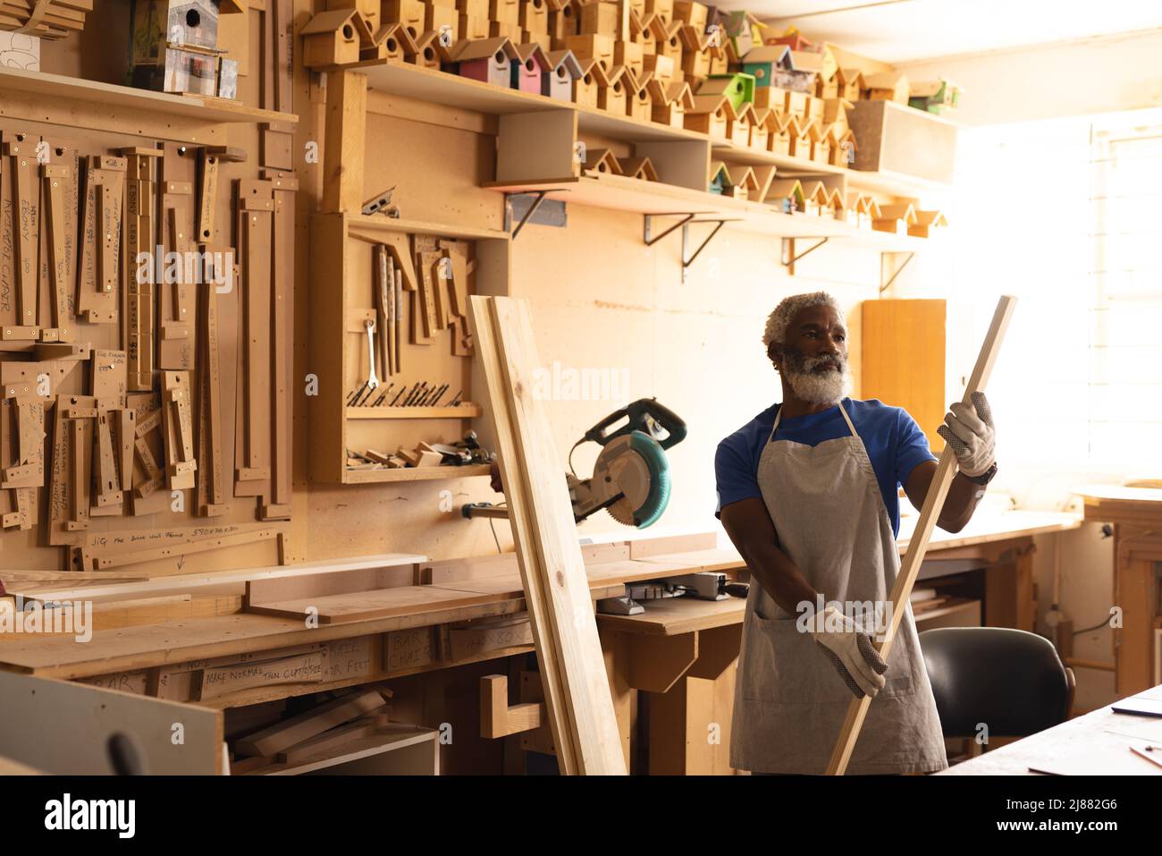 Falegname maturo afroamericano che esamina il legno in officina Foto Stock