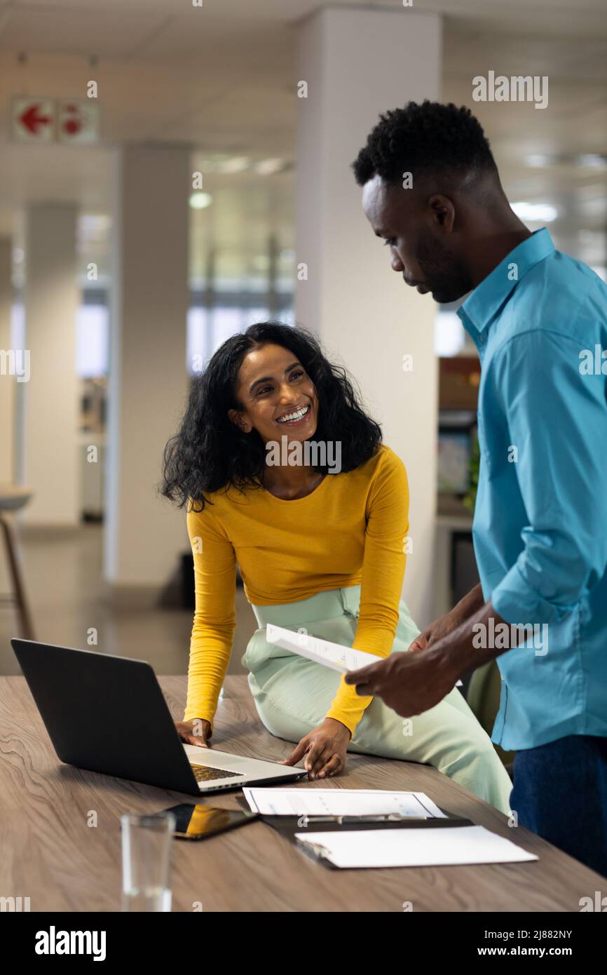 Sorridente donna d'affari biraciale guardando l'uomo d'affari afro-americano durante la riunione Foto Stock