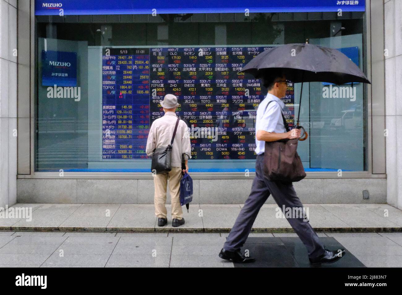 Tokyo, Giappone. 13th maggio 2022. Un uomo che tiene un ombrello cammina di fronte a un quadro elettrico mostrando Nikkei indice un brokerage a Tokyo. (Foto di James Matsumoto/SOPA Images/Sipa USA) Credit: Sipa USA/Alamy Live News Foto Stock