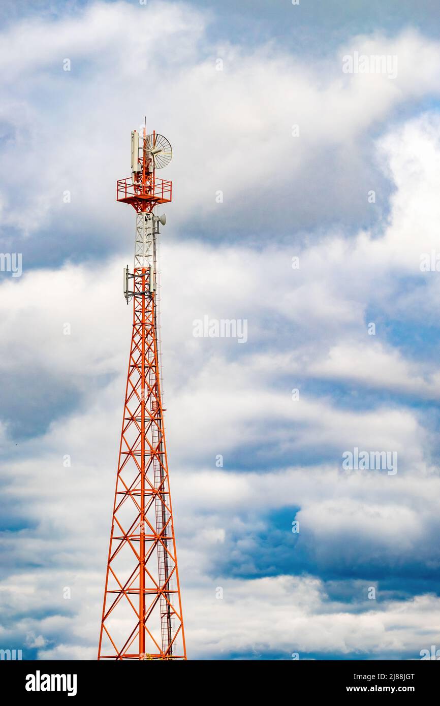 Palo radio (torre) con antenne per telecomunicazioni e trasmissioni e cielo nuvoloso tempestoso. Foto verticale a tutta lunghezza Foto Stock
