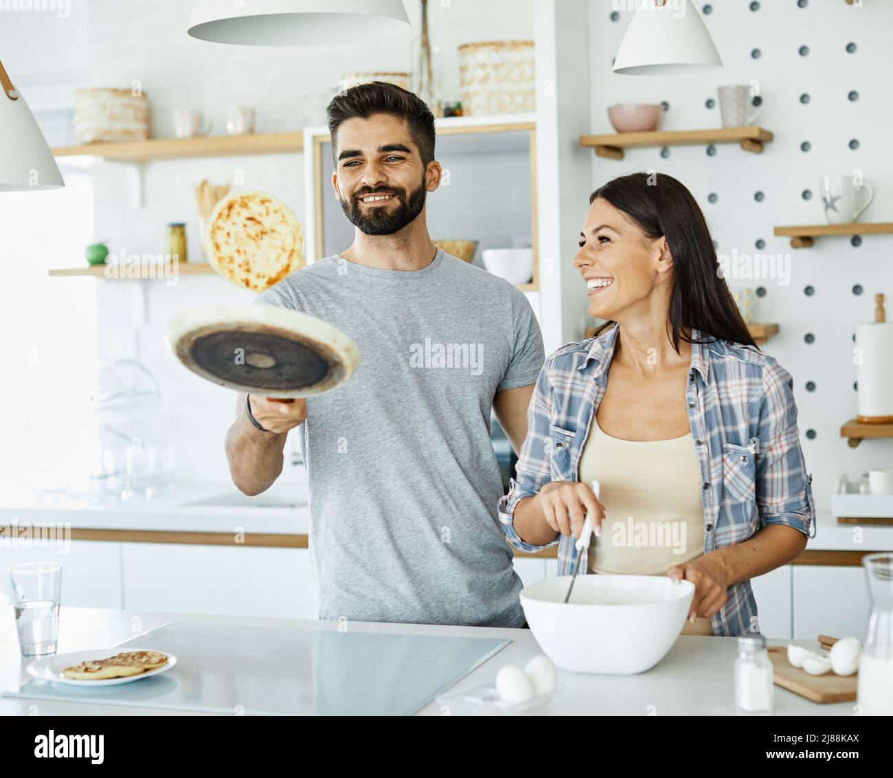 donna uomo coppia felice cucina amore giovane pancake insieme romantico ragazzo ragazza colazione Foto Stock