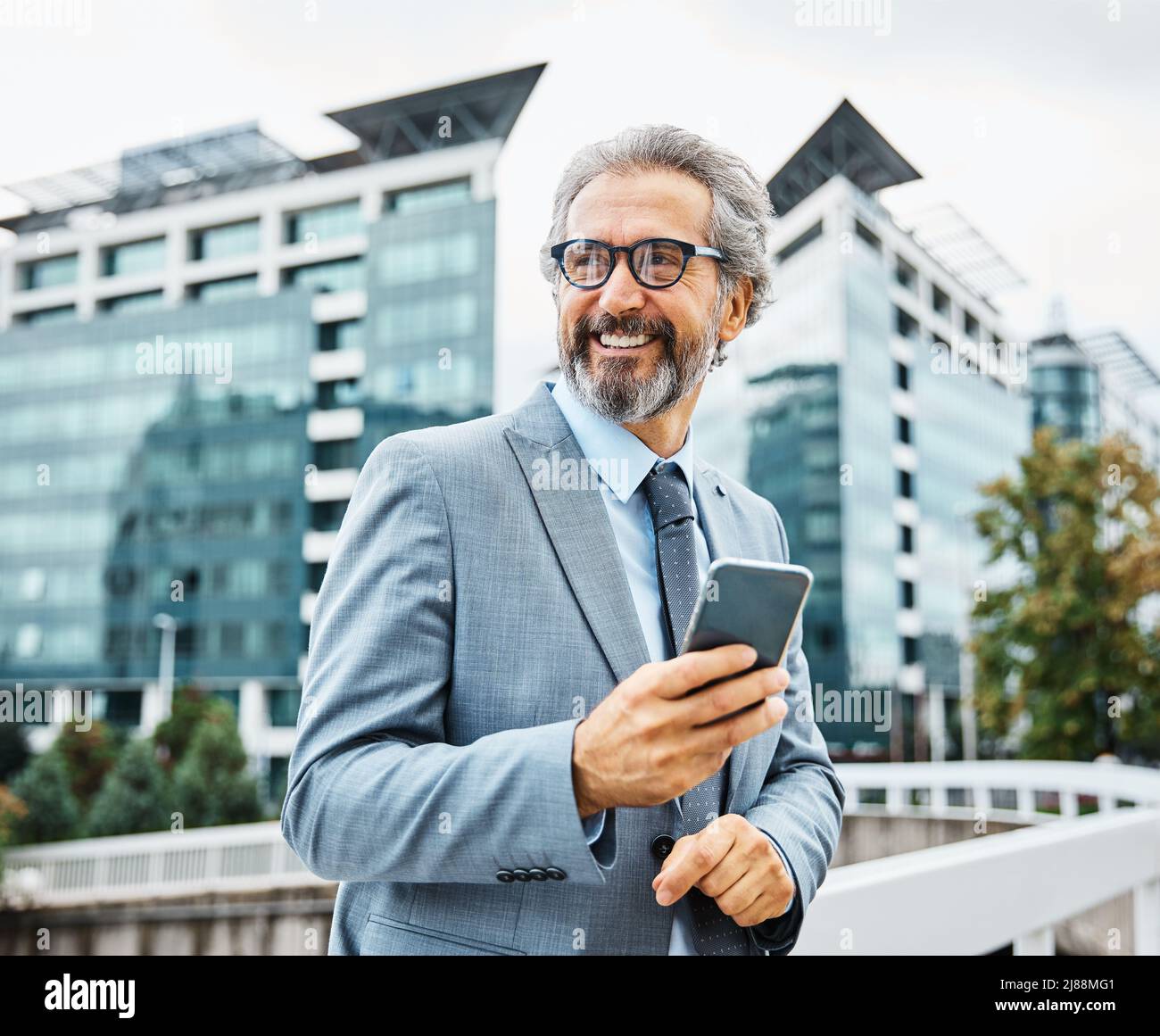 senior businessman ufficio edificio telefono cellulare all'aperto città smartphone comunicazione grigio capelli Foto Stock