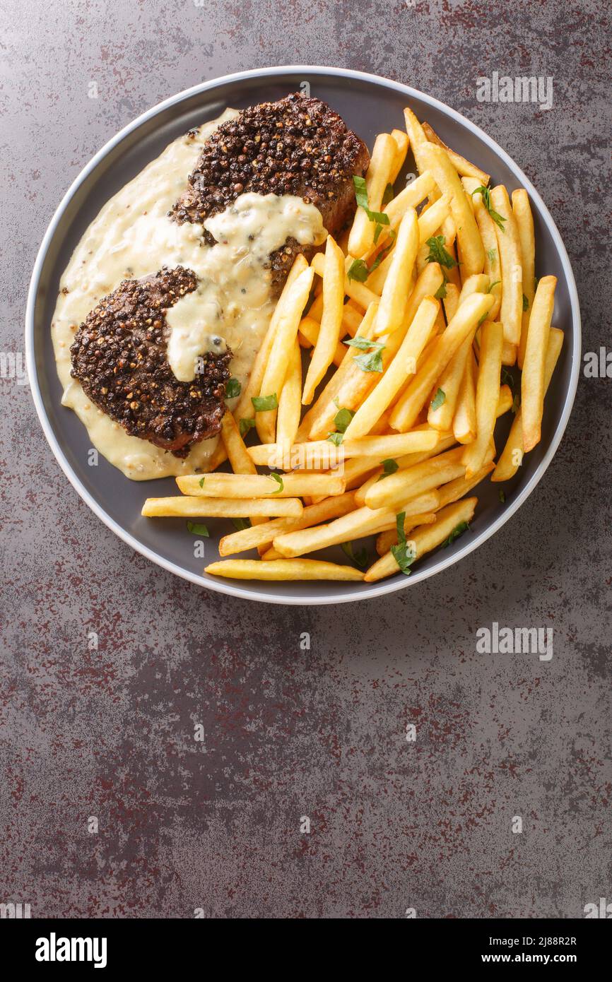 Steak au poivre o pepper steak è un piatto francese che consiste in un mignon di filetto, rivestito di pepe cracked grossolanamente servito con patatine fritte cl Foto Stock