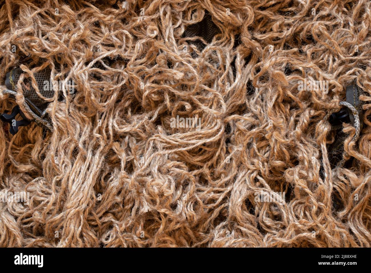 Un abito mimetico di un soldato scout fatto di corde marroni come sfondo, un mantello mimetico fatto di una griglia e una corda marrone Foto Stock