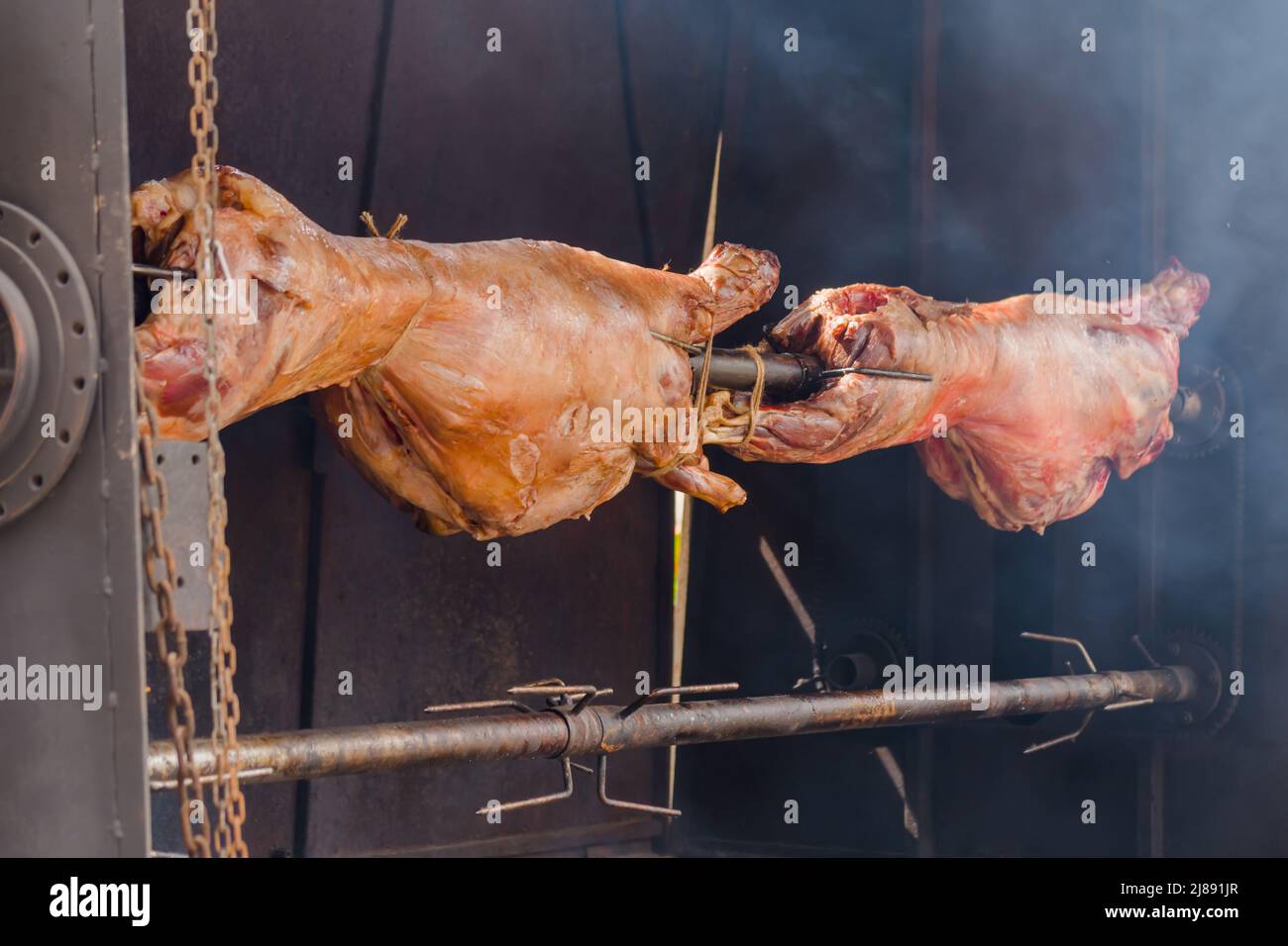 Processo di cottura delle carcasse di ariete su spit al mercato di Street food estivo: Primo piano Foto Stock