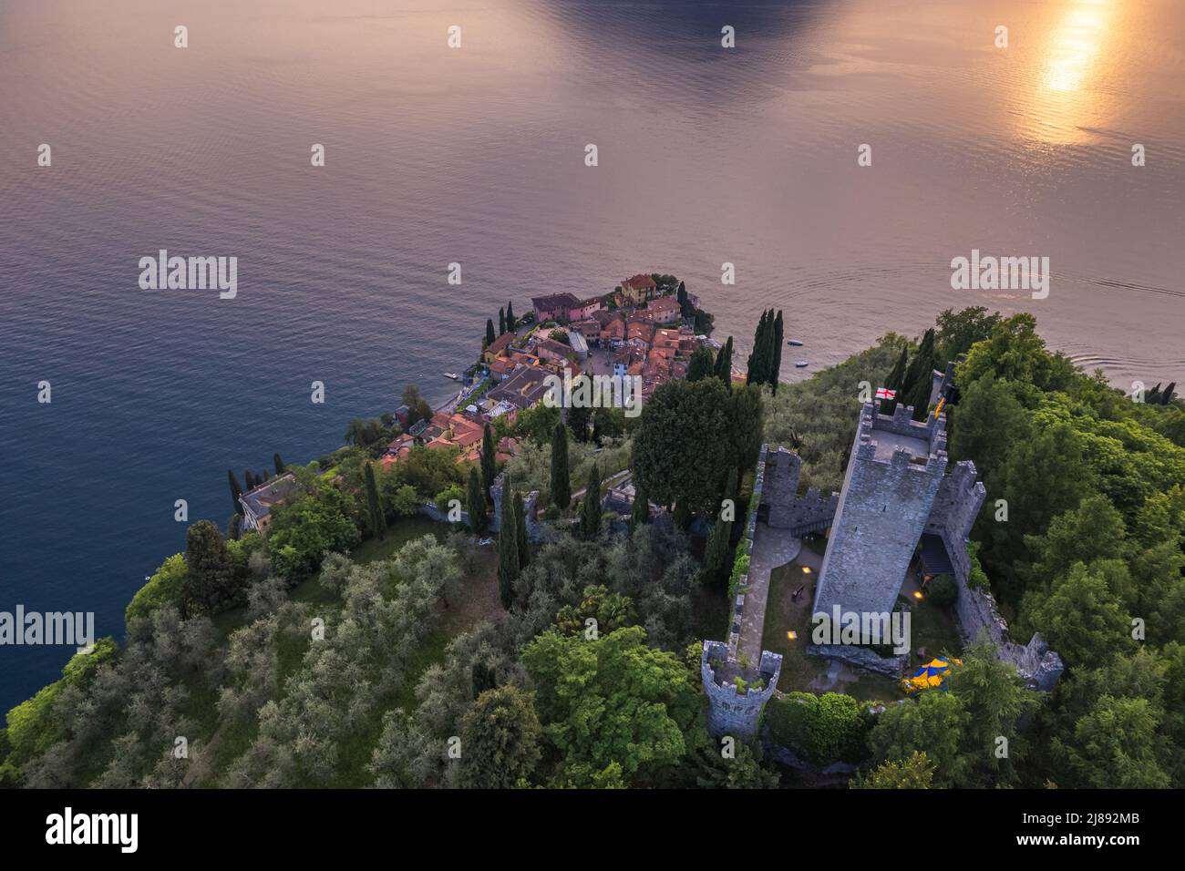 Veduta aerea del Castello di Vezio e del borgo di Varenna sullo sfondo durante il tramonto estivo. Fuco girato nel lago di Como. Varenna, Italia Foto Stock