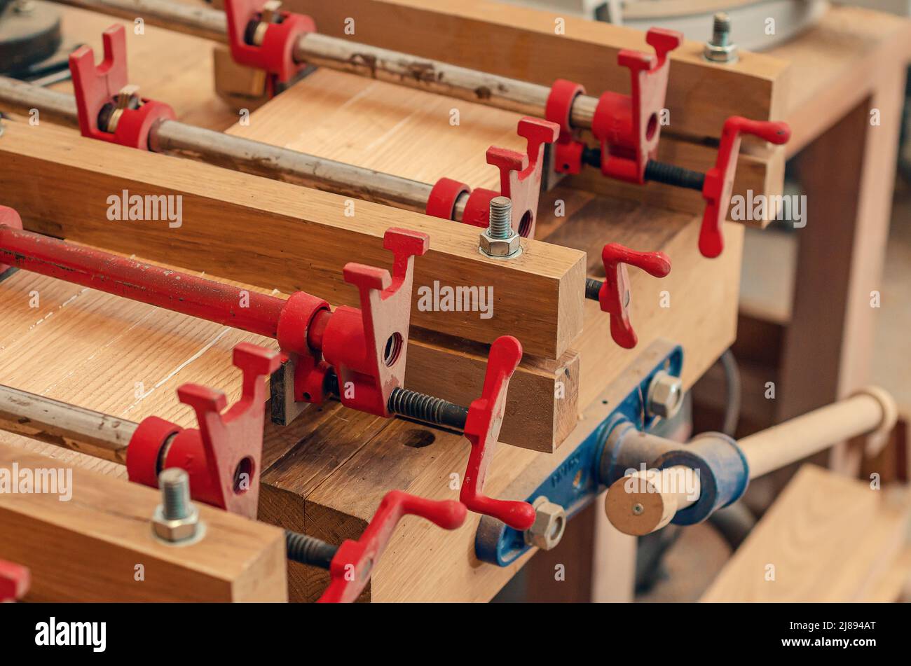 Primo piano dell'asse di fissaggio del carpentiere con morsetti. Falegnameria Foto Stock