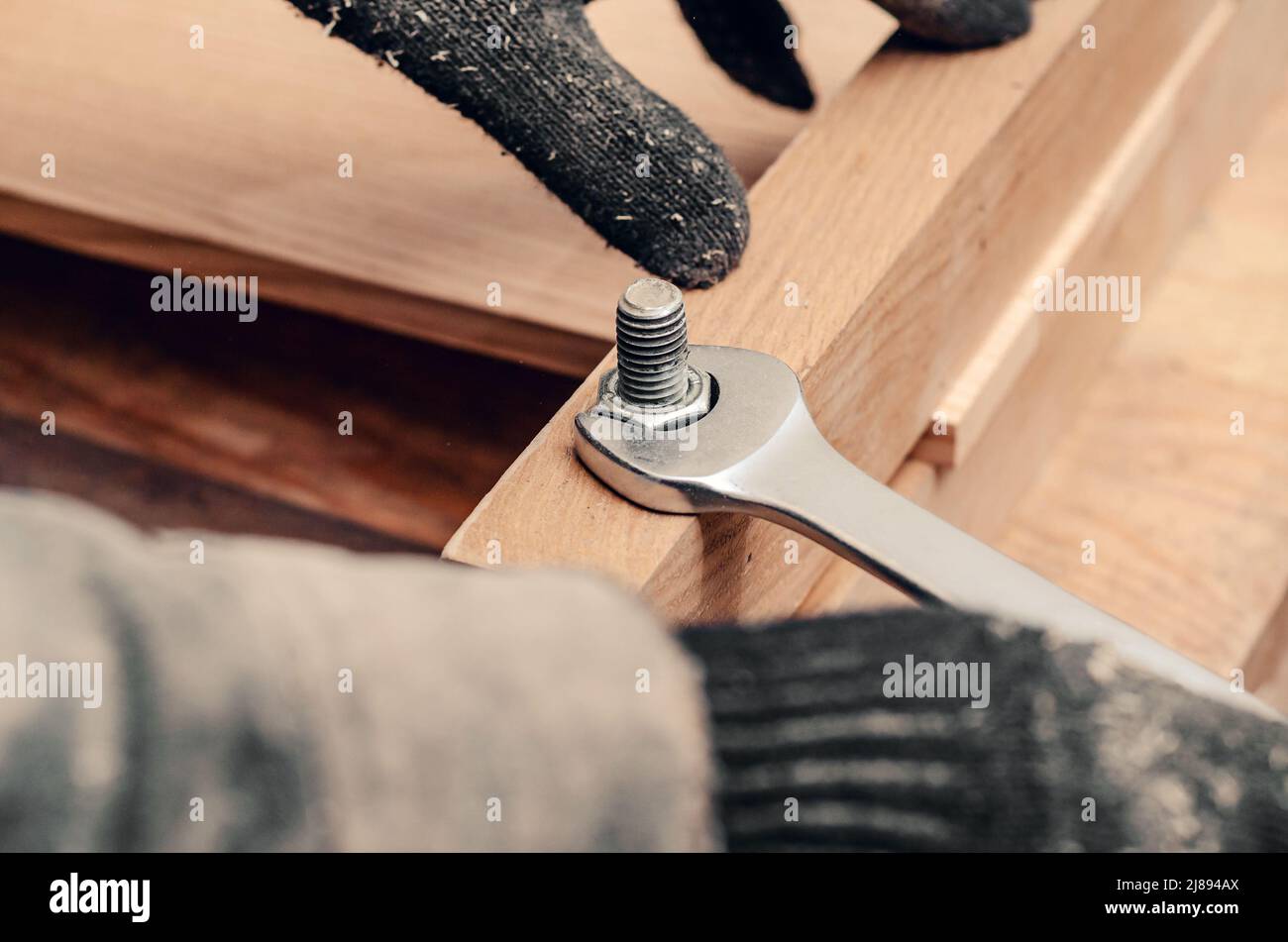 Serrare a mano maschio il dado sulla filettatura del bullone avvitato nella struttura in legno. Foto Stock