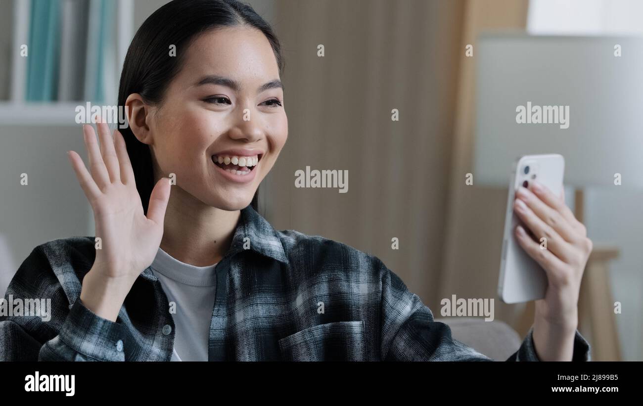Felice ragazza asiatica amichevole blogger vlogger sorridente femmina lontana donna cellulare video chiamata comunicazione remota saluto wonding mano parlare Foto Stock