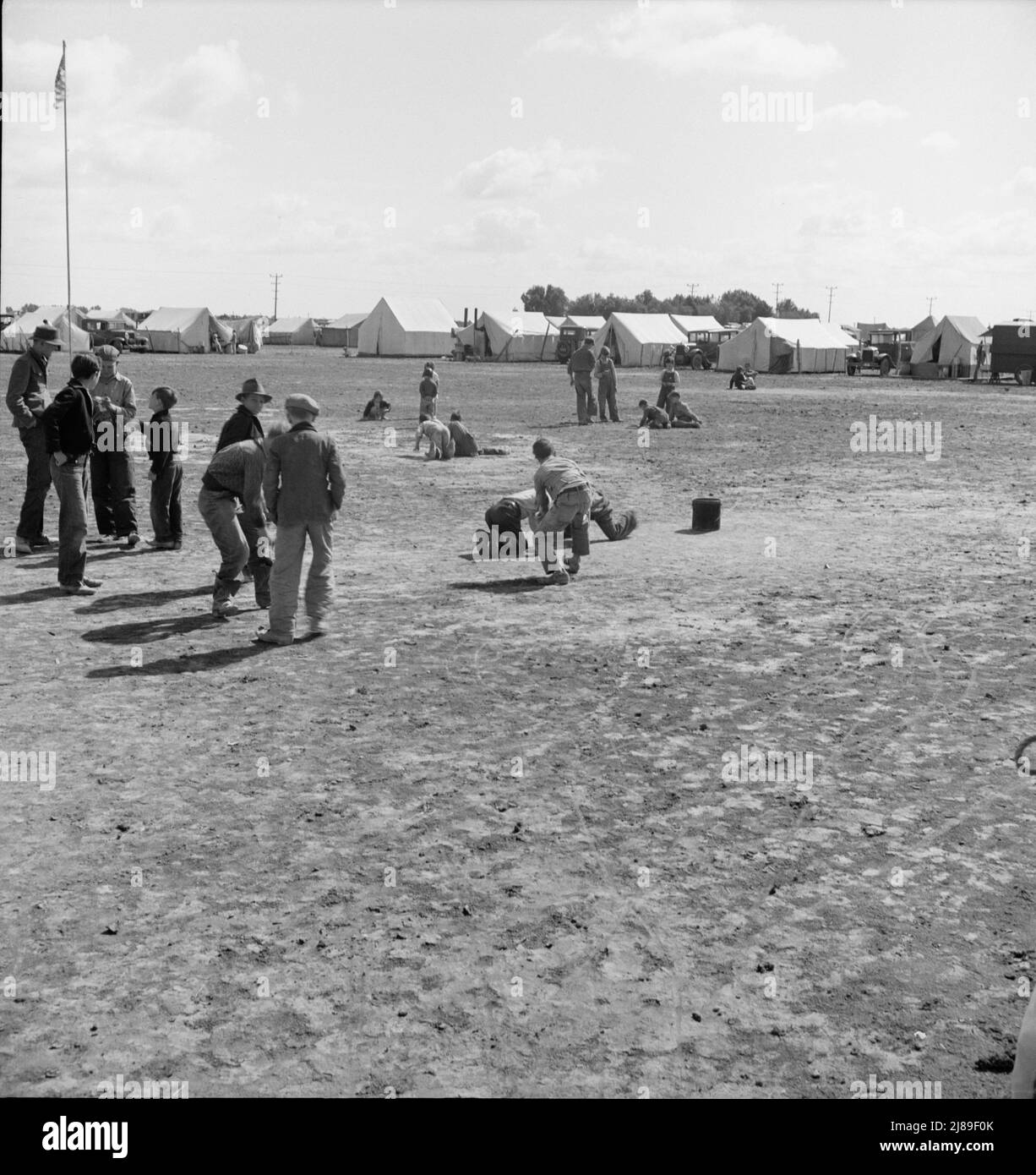 Marble Time in Farm Security Administration (FSA) campo di lavoro migratorio (emergenza.) Molto spazio per giocare e molti compagni per i bambini durante la raccolta dei piselli. Vicino a Calipatria, Imperial Valley, California. Foto Stock