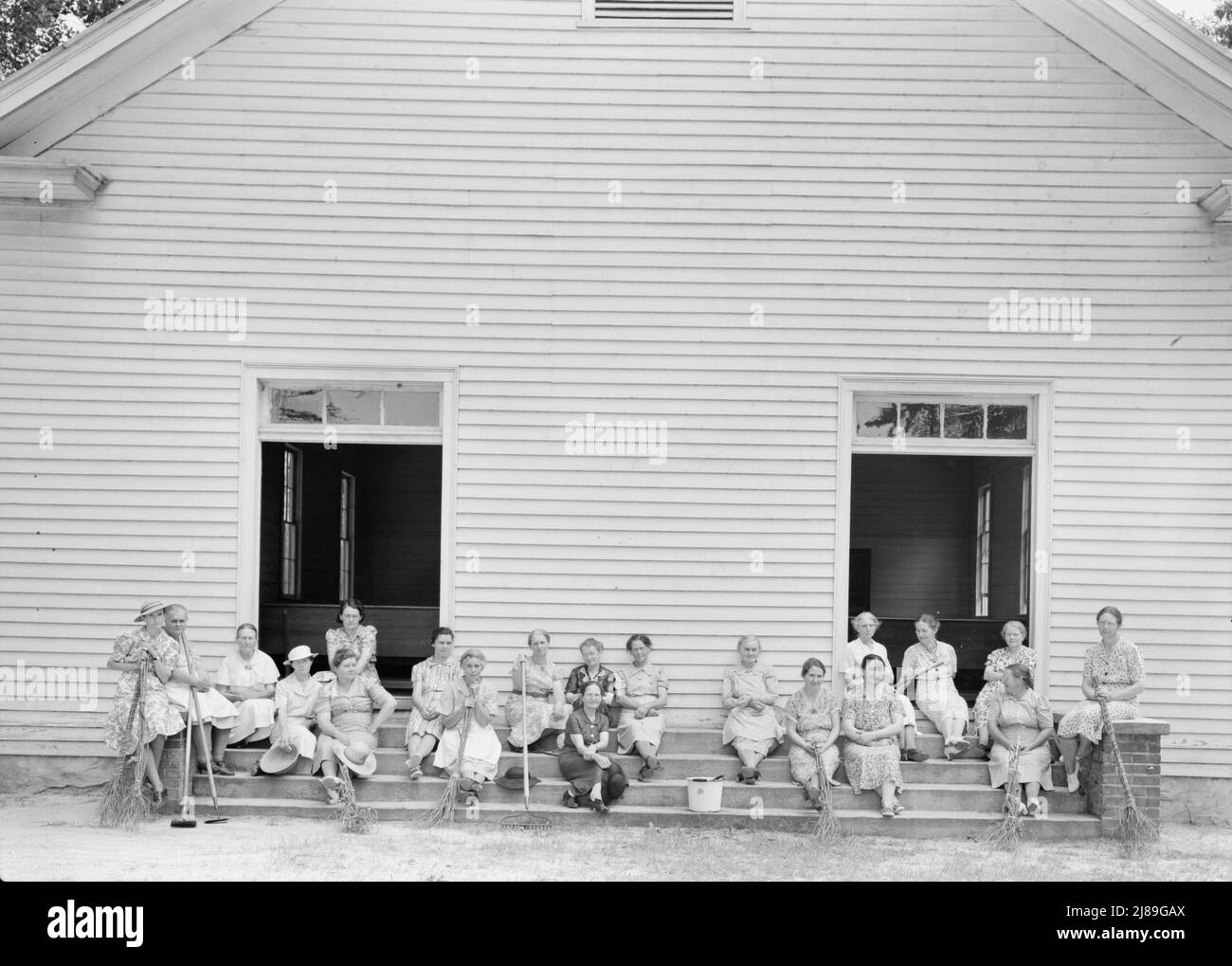 Donne della congregazione della Chiesa di Wheeley su gradini con scopa e secchielli il giorno di pulizia annuale. Gordonton, Carolina del Nord. Foto Stock