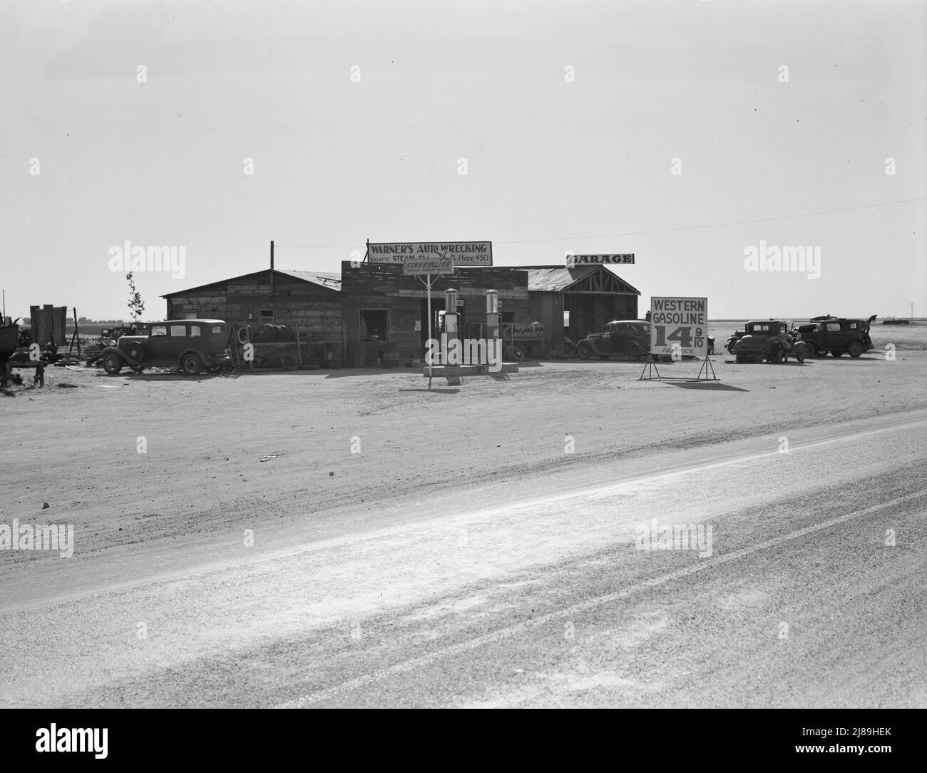 Tra Tulare e Fresno, California. [Distributore di benzina e garage - indicazioni: 'Stramline - Norwalk Premium Gasoline; Warner's Auto Wrecking; Garage; Western Gasoline - 14 9/10 Full Price']. Foto Stock