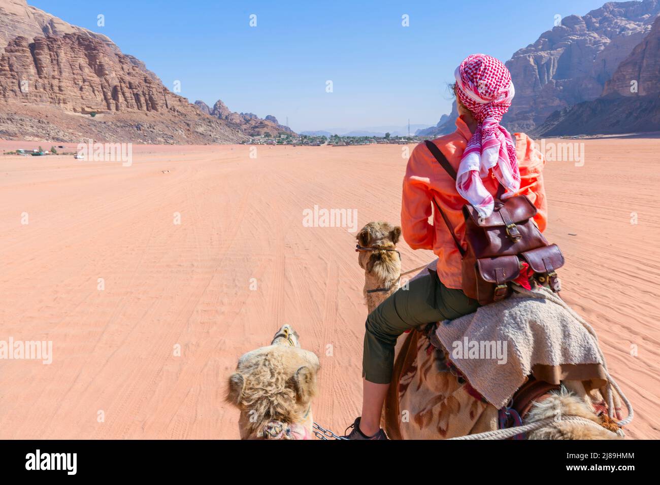 Bella giovane donna turista in abito bianco a cavallo sul cammello nel deserto di rum wadi, Giordania Foto Stock