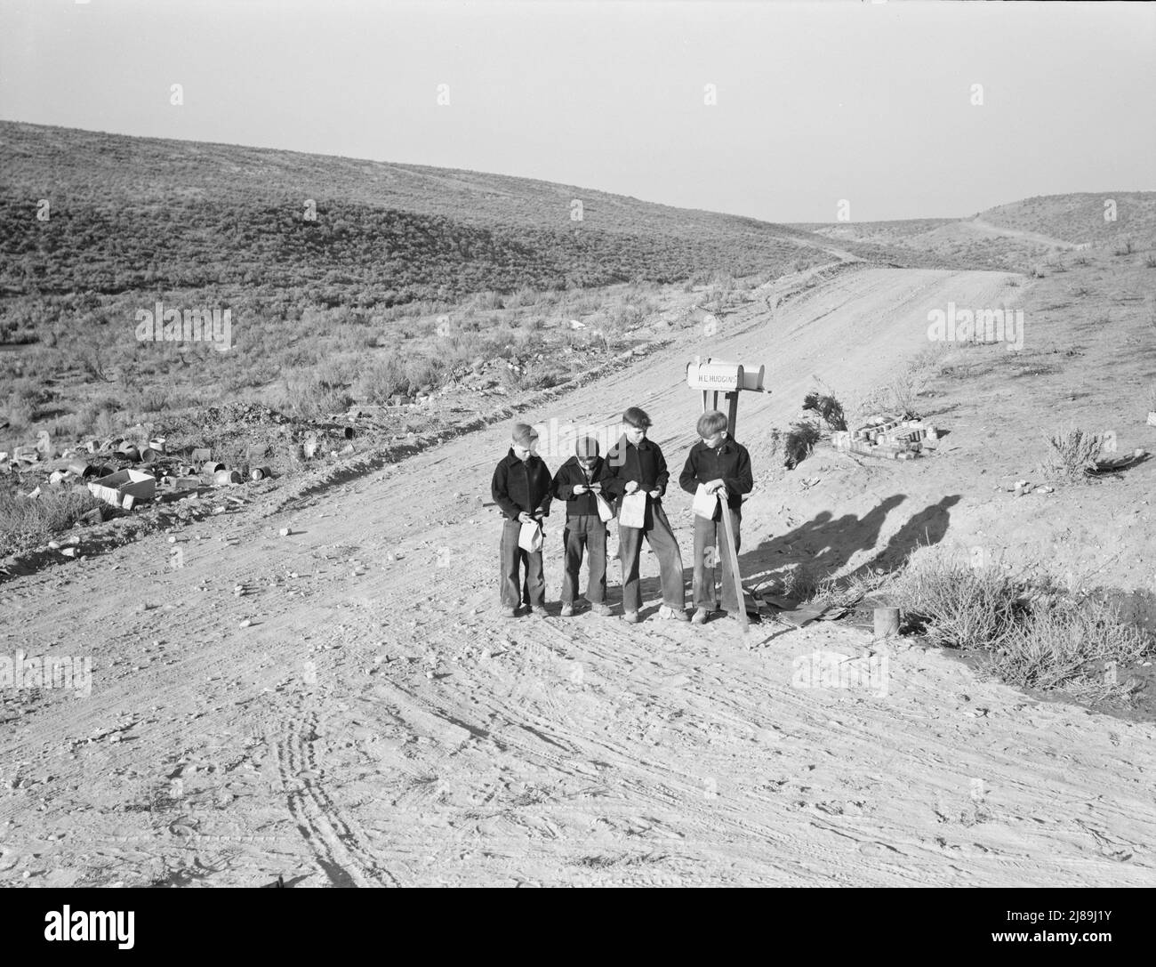 I ragazzi aspettano il bus della scuola la mattina. Malheur County, Oregon. Foto Stock