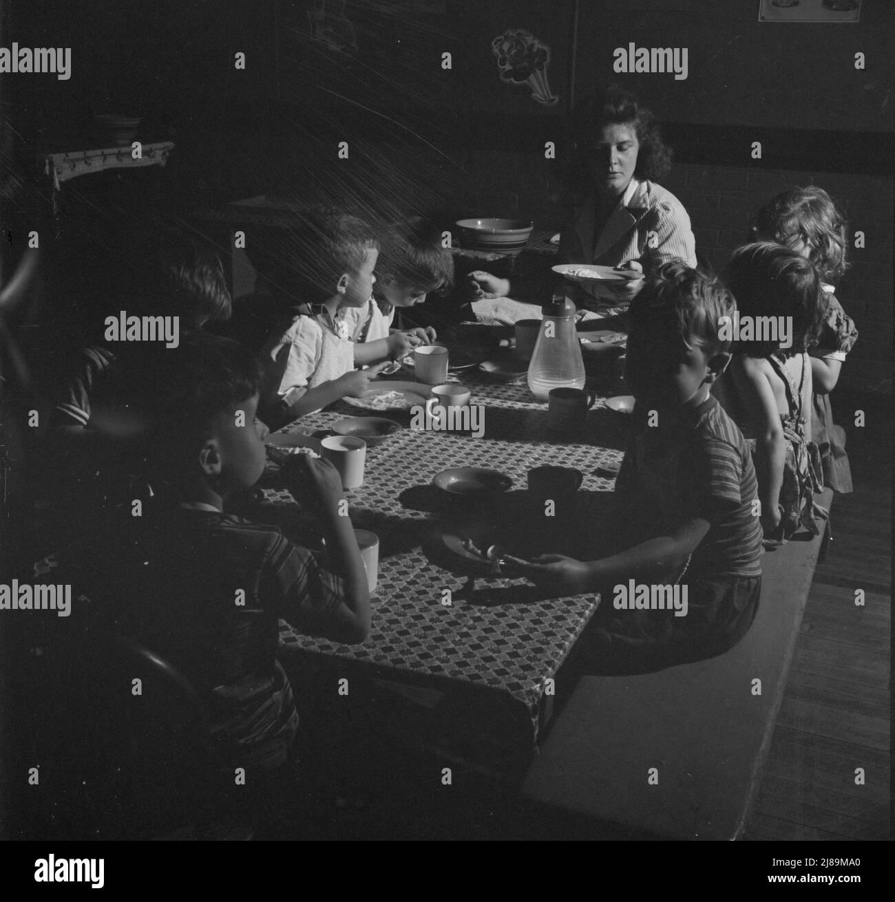 [Foto senza titolo, probabilmente legata a: New Britain, Connecticut. Un centro di assistenza bambini, aperto il 15 settembre 1942, per trenta bambini, di età compresa tra i due e i cinque anni, di madri impegnate nell'industria bellica. Orario: Dalle 6:30 alle 6:00, sei giorni alla settimana. I bambini pranzano con un assistente addestrato]. Foto Stock