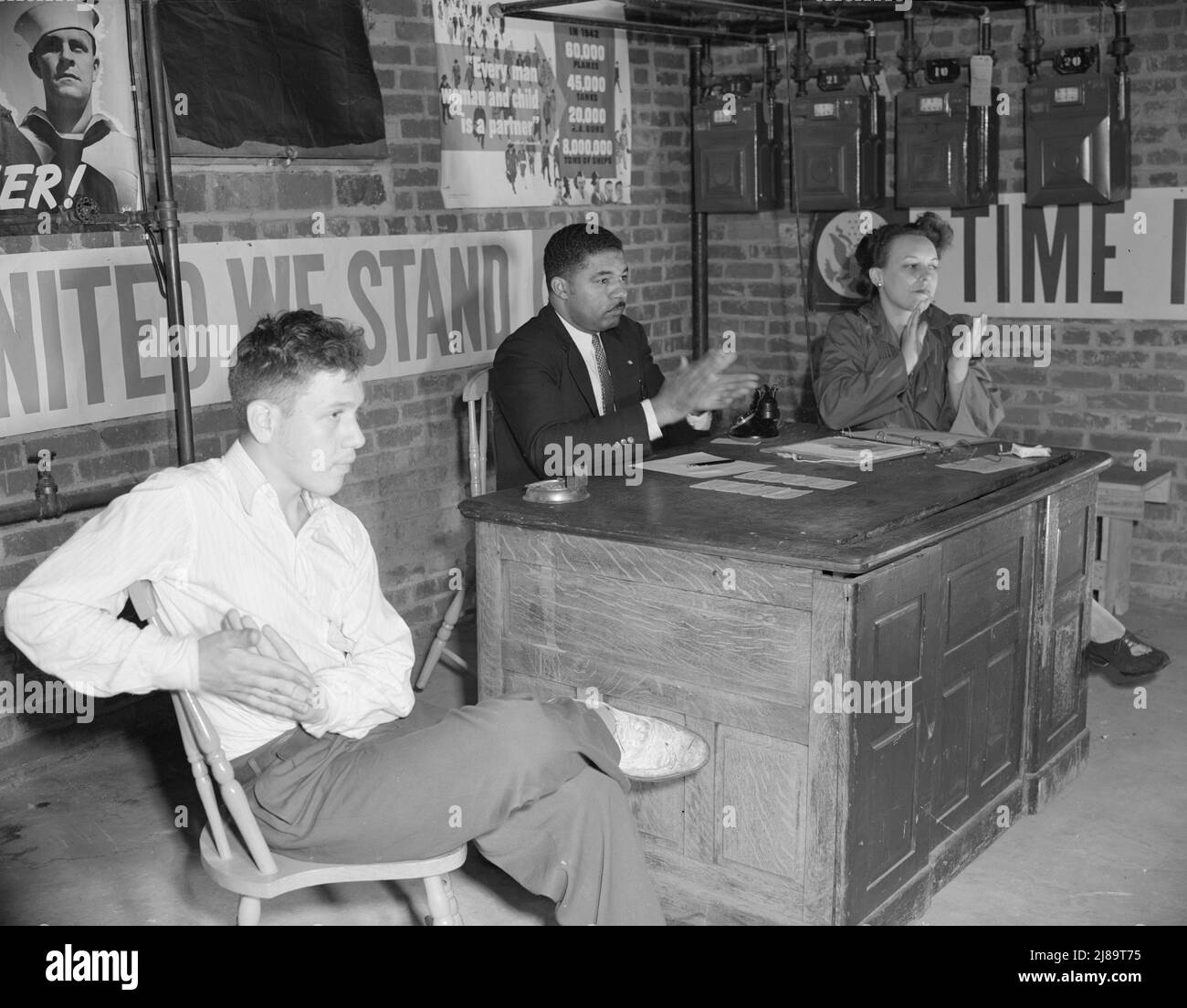 Washington, D.C. Air raid Wardens' meeting in zona nove, zona sud-ovest. Presidente, segretario e messaggero applaudono la relazione di un guardiano. Sidney Goldstein, il messaggero, è il figlio della drogheria del quartiere. Foto Stock