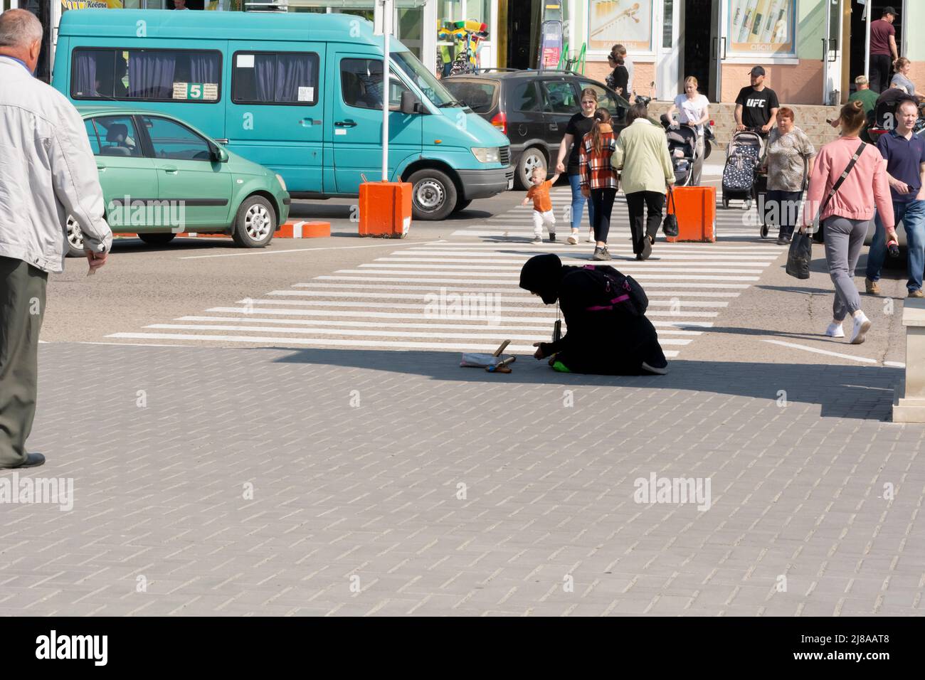 Tiraspol, Moldavia - 13 maggio 2022: Una mendicante implora vicino al parco, inginocchiandosi e pregando. Problemi sociali nei paesi dell'ex URSS, l'unreco Foto Stock