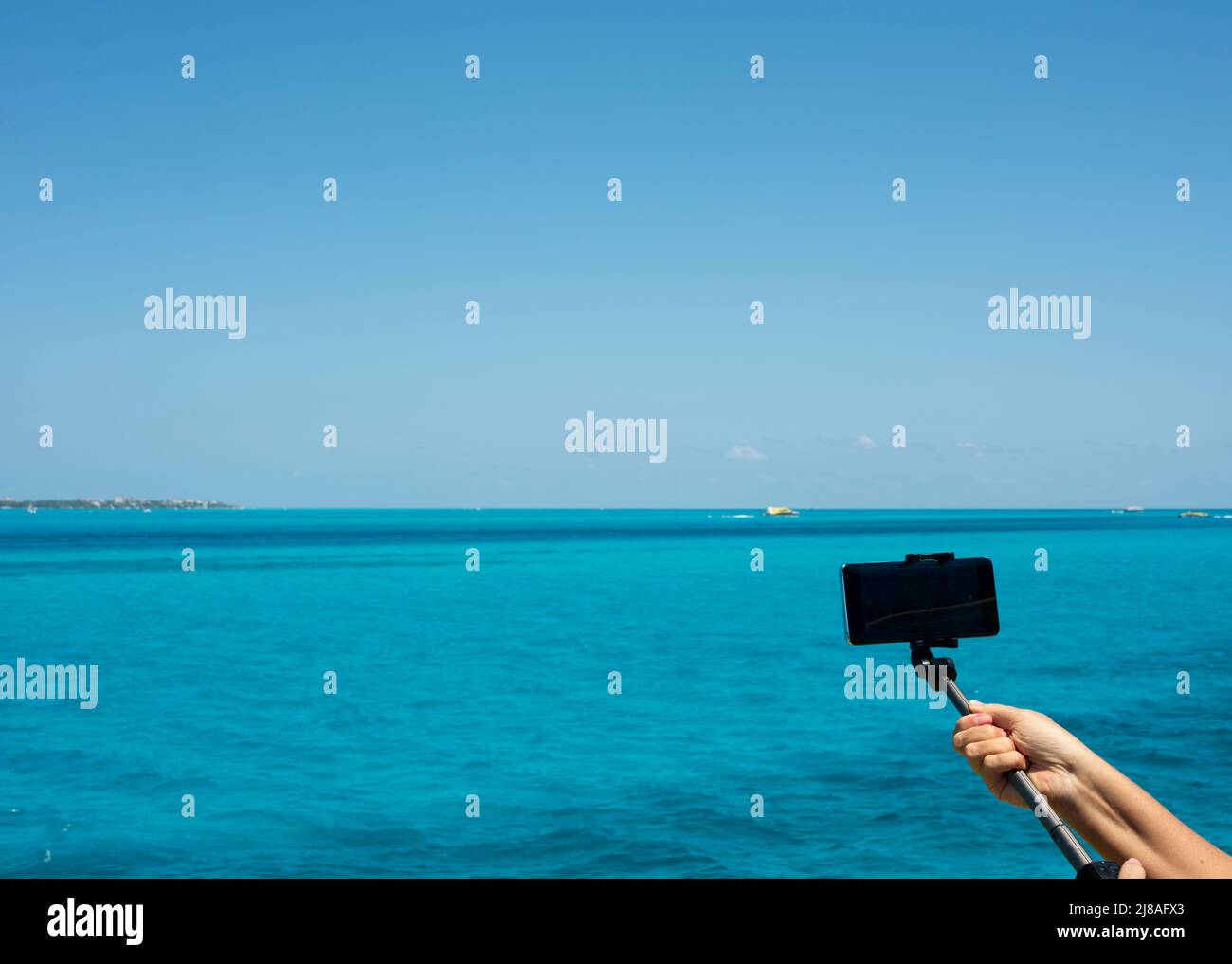 Braccio di una donna con uno smartphone prende video mentre navigano nel Mar dei Caraibi in Messico Foto Stock