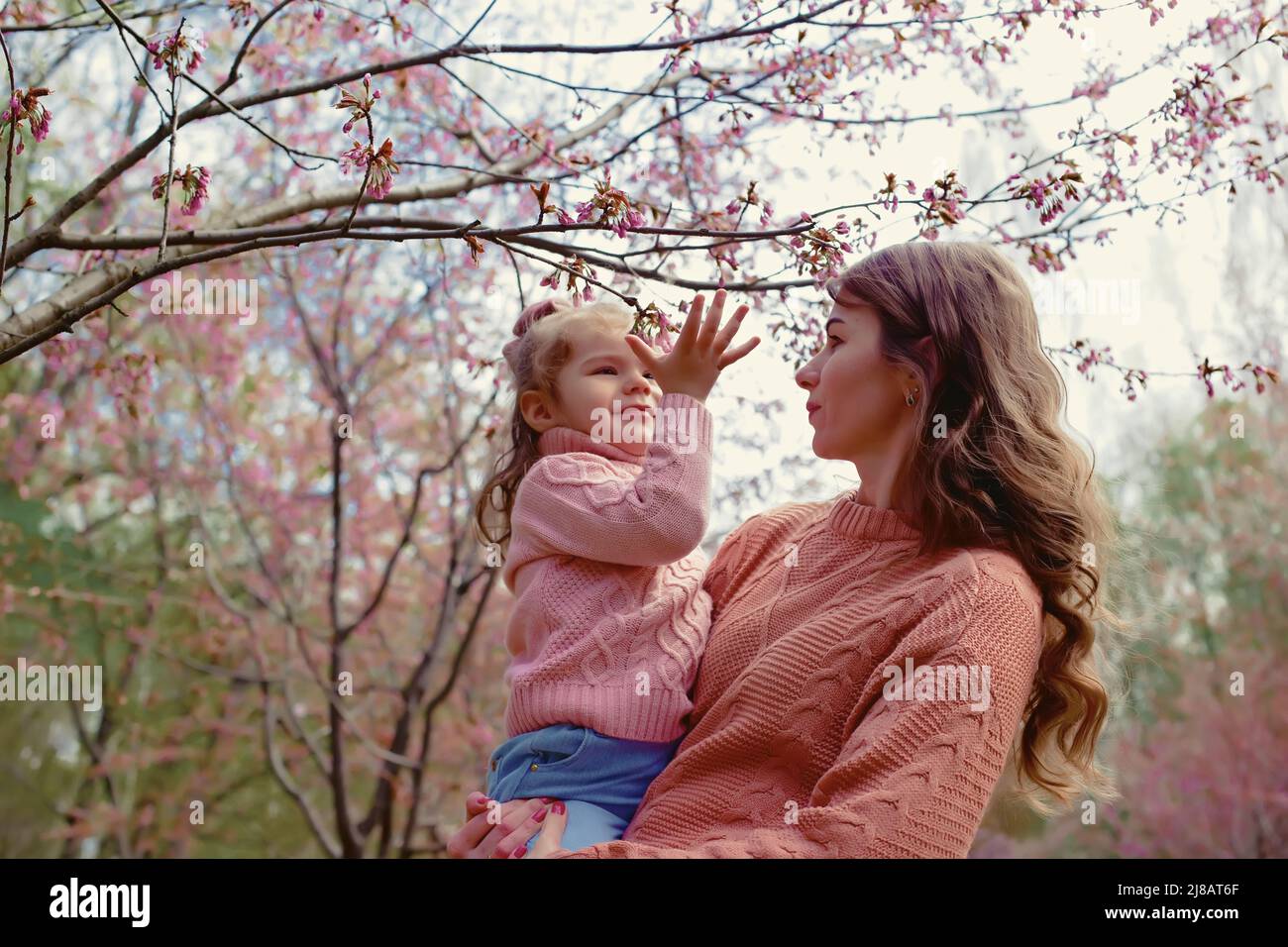 Madre e bambina, in piedi nel parco sotto un albero di fiori Foto Stock