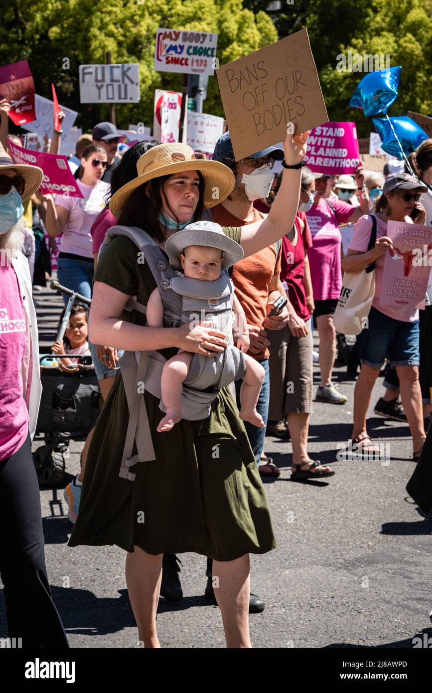 Foto di una donna che tiene un bambino e segno di protesta durante il Roe divieti fuori i nostri corpi marcia e Rally organizzato da Planned Parenthood. Foto Stock