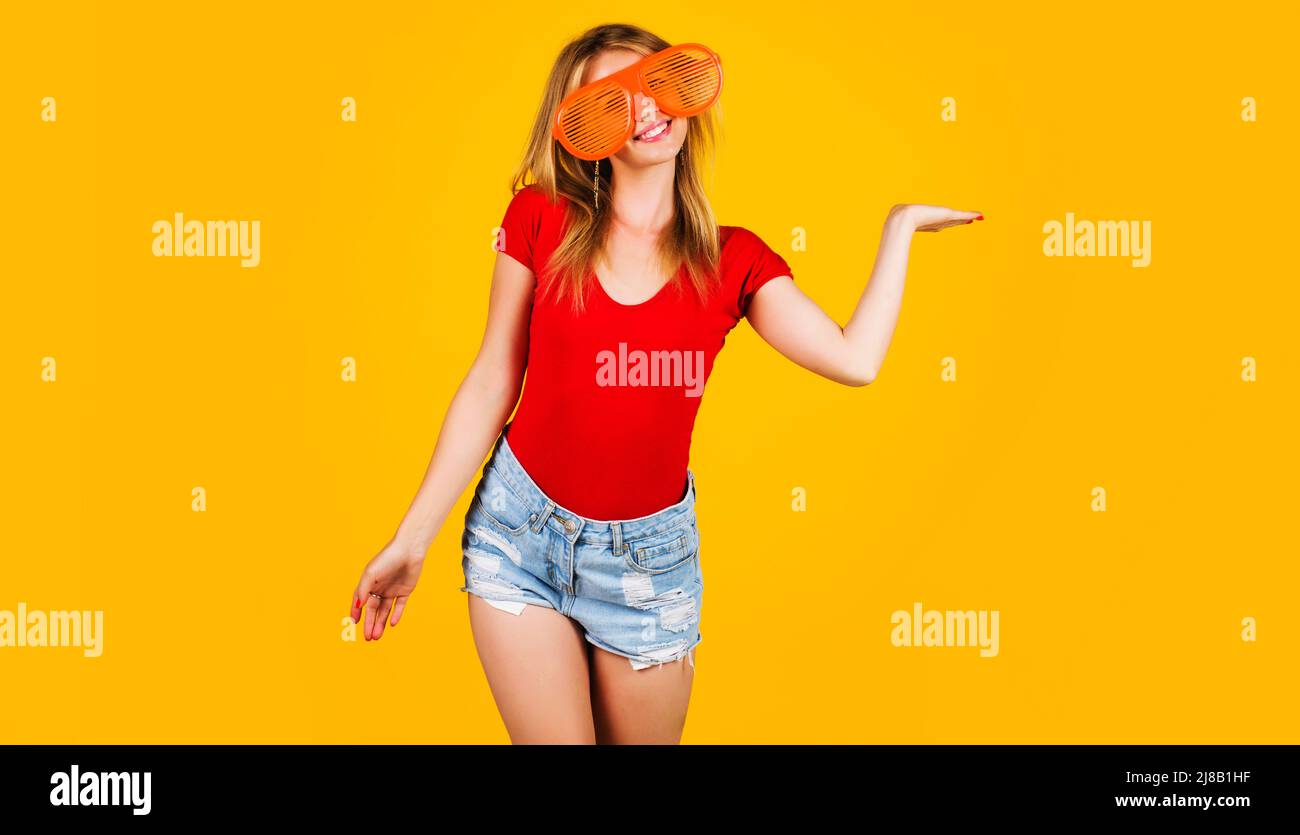 La donna sorridente tiene qualcosa sul palmo aperto. Ragazza divertente in grandi occhiali. Sconti e sconti stagionali. Foto Stock