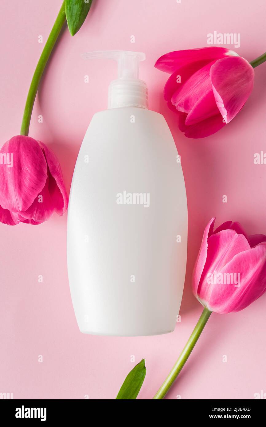 Prodotti per la cura della pelle Spa su sfondo rosa. Cosmetici naturali e tulipani rossi. Posiziona per il testo. Foto Stock