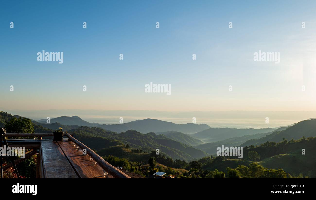 Tavolo in legno. Paesaggio naturale di montagne e cielo blu con luce del sole al mattino. Foto Stock