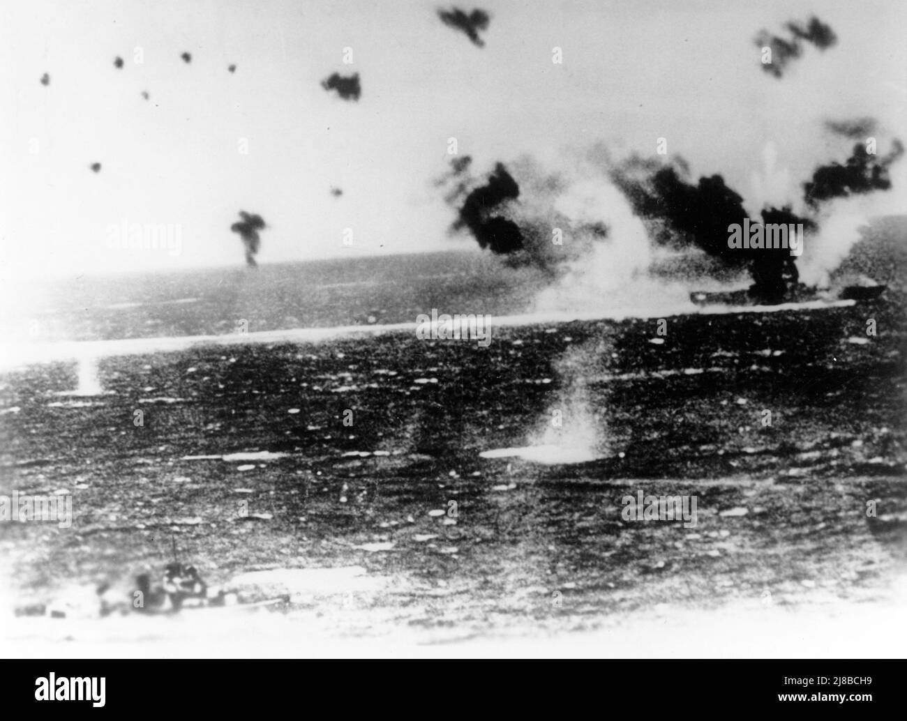 Il portaerei della Marina degli Stati Uniti USS Lexington (CV-2) sotto attacco aereo il 8 maggio 1942 durante la Battaglia del Mare dei Coralli, come fotografato da un aereo giapponese. Il fumo nero pesante dalla sua pila e il fumo bianco dalla sua prua indicano che la vista è stata presa subito dopo quelle zone sono state colpite dalle bombe. Il cacciatorpediniere in basso a sinistra sembra essere USS Phelps (DD-360). Foto Stock