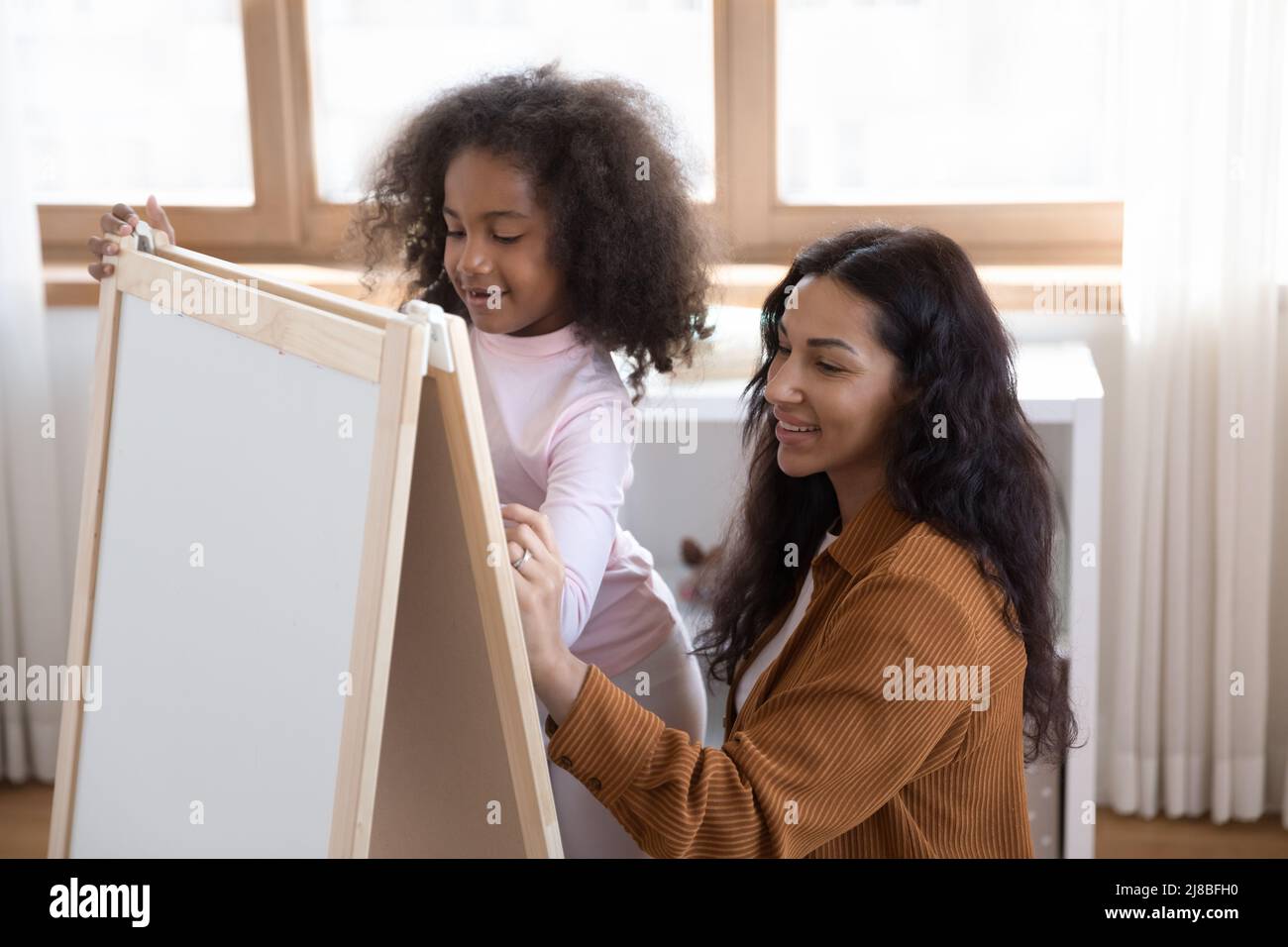 Madre africana sua figlia piccola che disegnano le immagini sulla lavagna Foto Stock