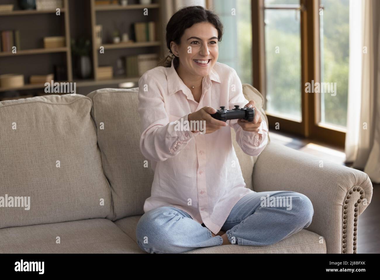 Donna seduta sul divano hanno divertimento giocare video gioco online Foto Stock