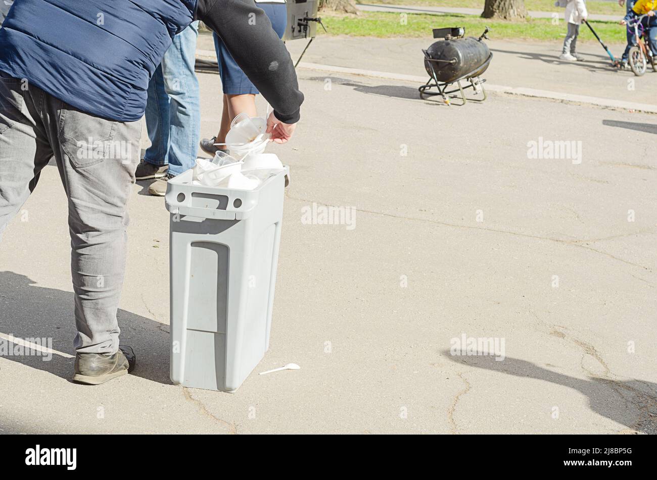 L'uomo mette la plastica usa e getta stoviglie in contenitore di plastica sulla strada.riciclaggio rifiuti di plastica Foto Stock