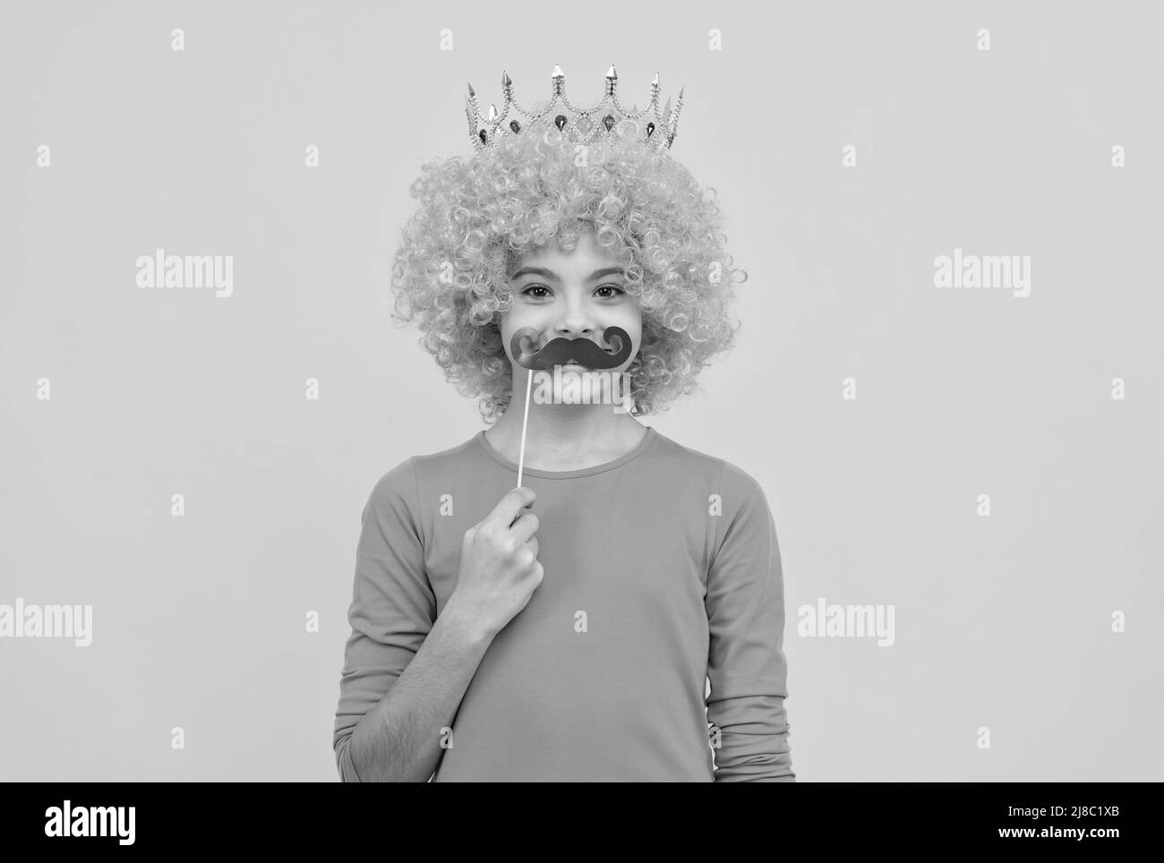 ragazza allegra egoista bambino in parrucca curly e principessa diadem indossare baffi partito, festa Foto Stock