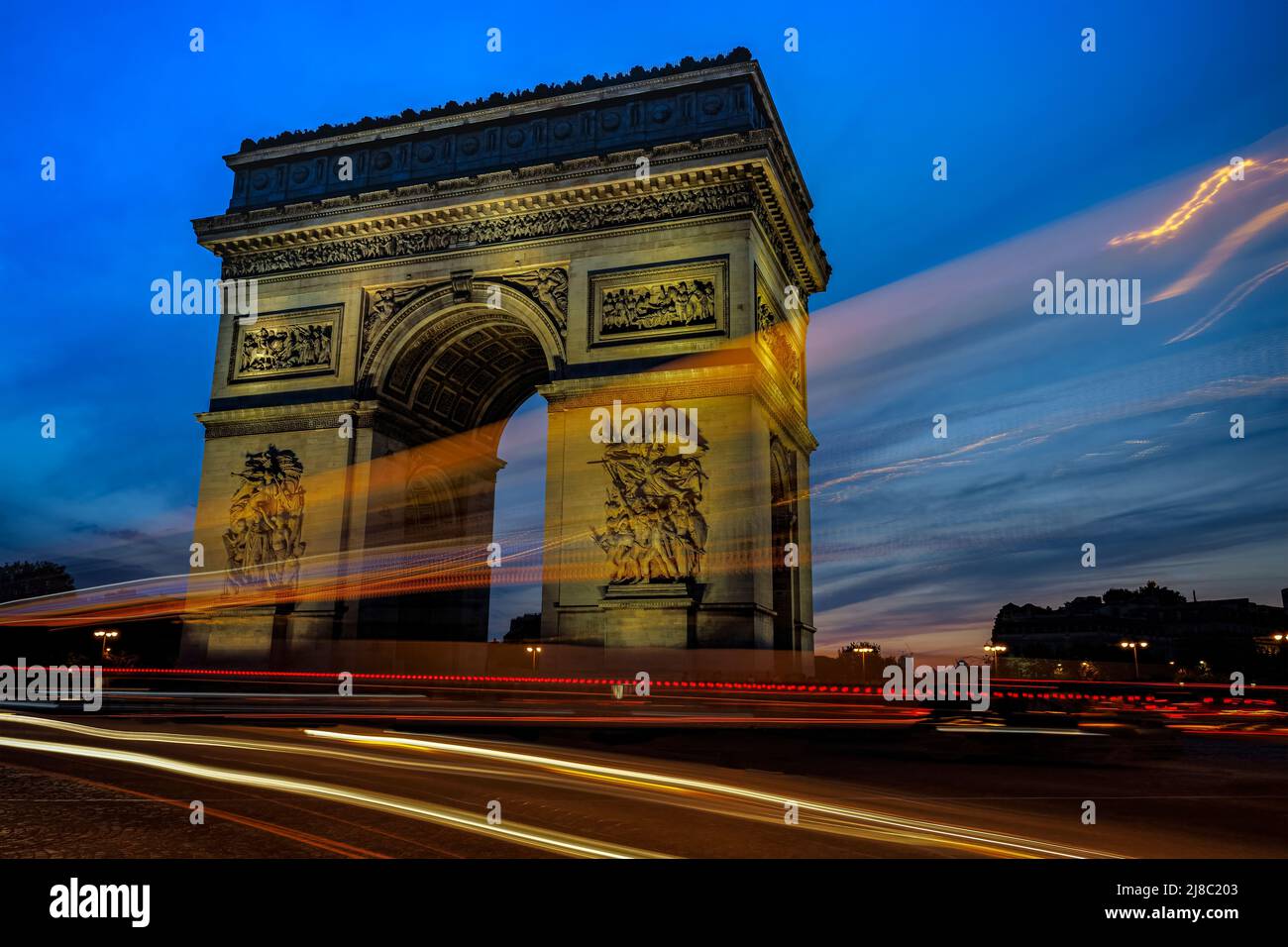 L'Arco di Trionfo con tracce di traffico di luce durante un tramonto drammatico. Foto scattata il 22nd aprile 2022 a Parigi, Francia. Foto Stock