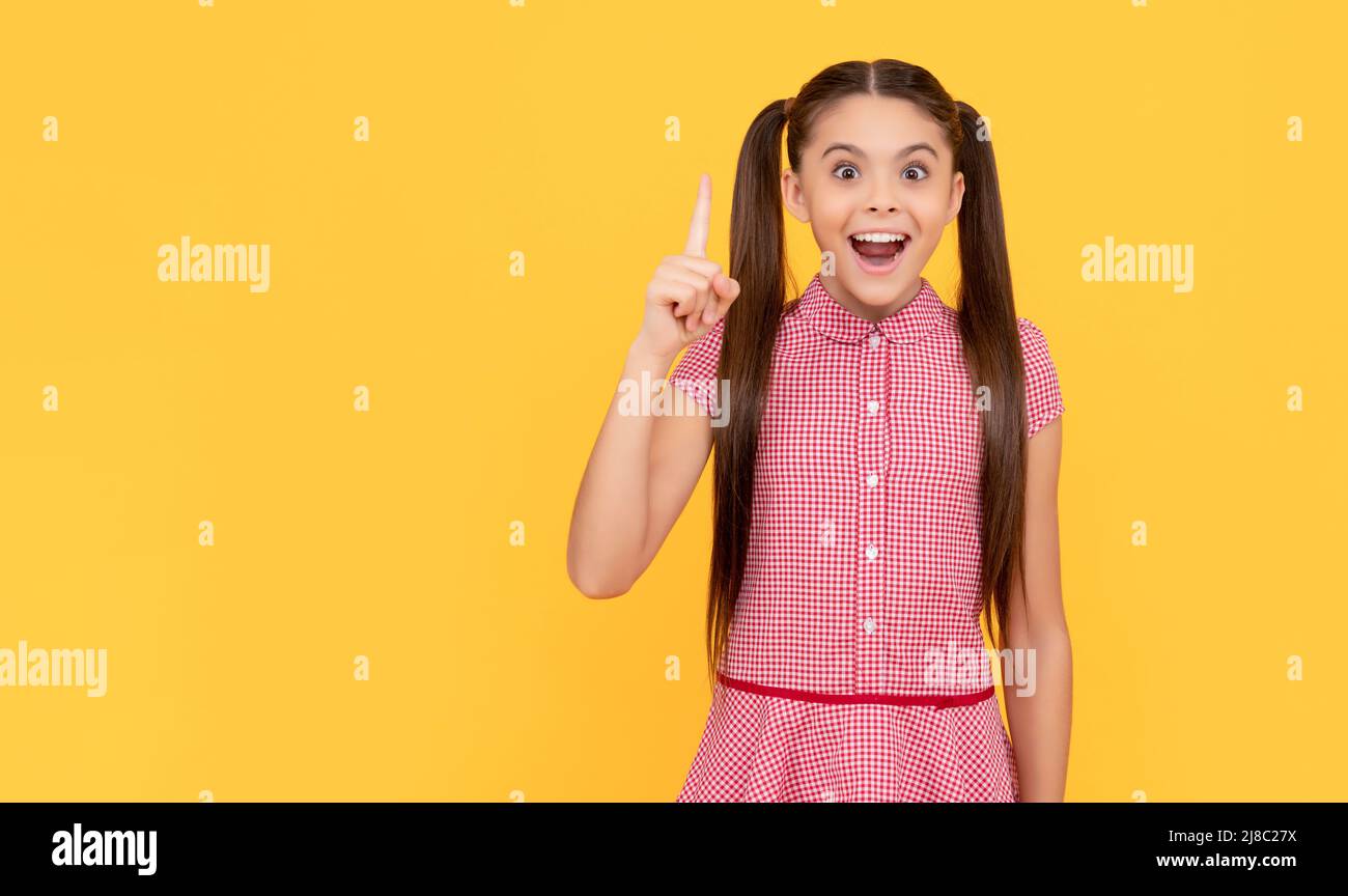 Felice ragazza genio bambino ha avuto idea puntando dito su sfondo giallo, eureka Foto Stock