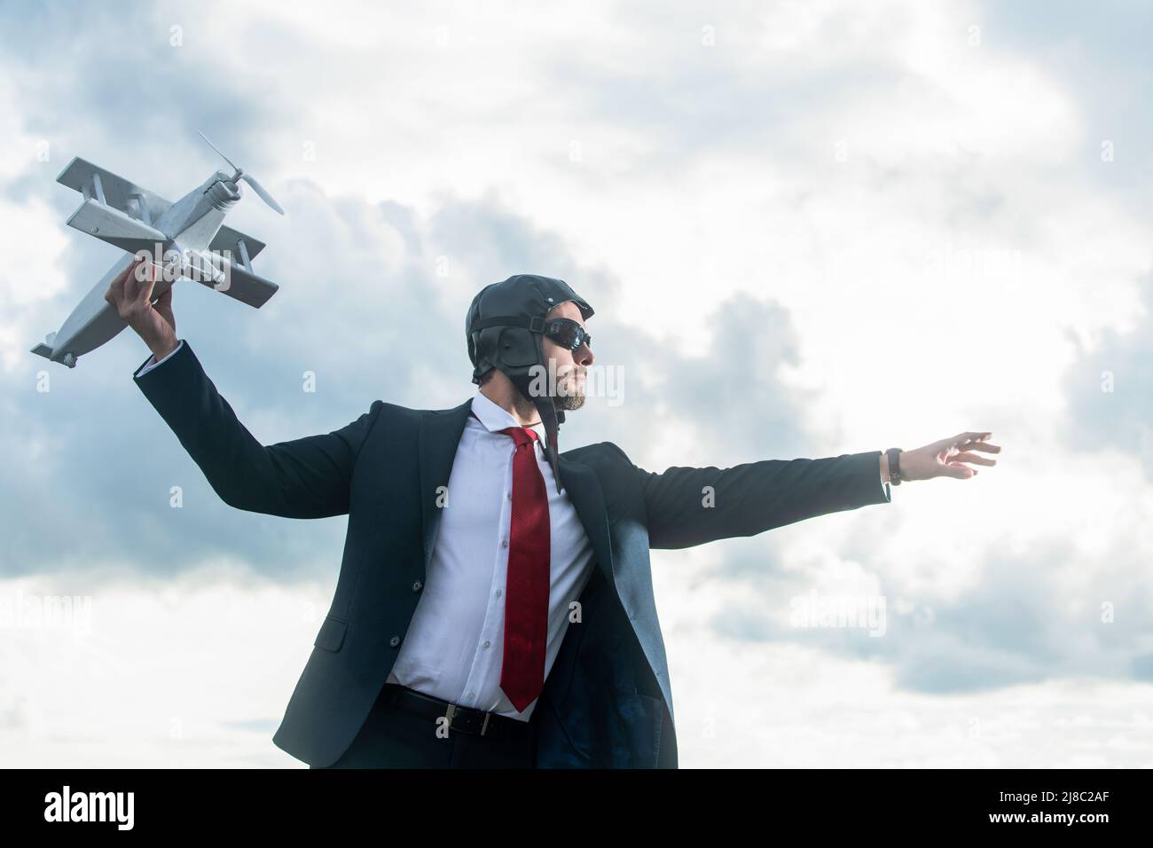 uomo d'affari in abito e cappello pilota lancia giocattolo aereo. concetto di start-up Foto Stock