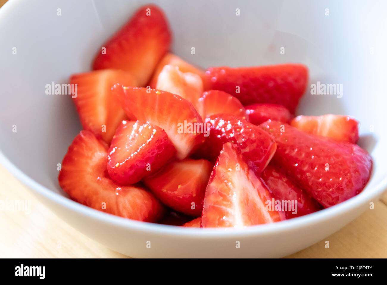 Molte fragole tagliate in ciotola sono pronte da mangiare con cucchiaio d'argento o come delizioso dito e snack sano con frutta rossa e vitamine su legno Foto Stock