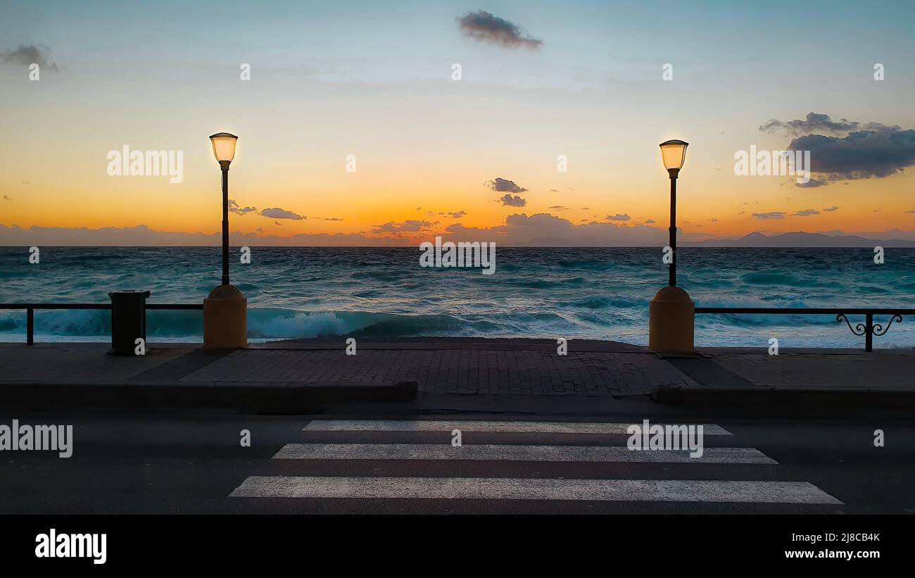 La spiaggia di Rodi Grecia al tramonto e due luci di strada e linee di crosswalk Foto Stock