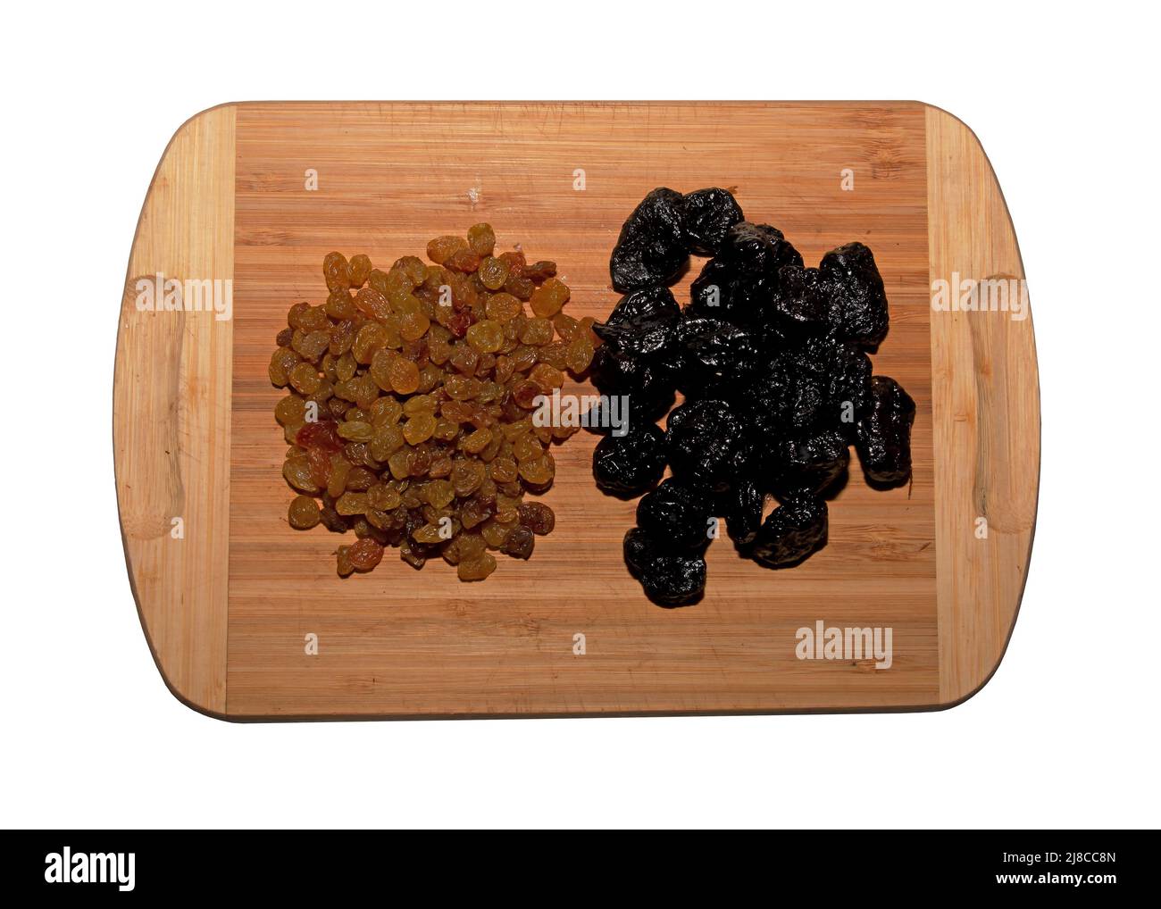 Una manciata di uvetta secca e prugne su un tavolo da cucina in legno. Sfondo di frutta secca. Concetto di cibo sano. Isolare su sfondo bianco. Foto Stock