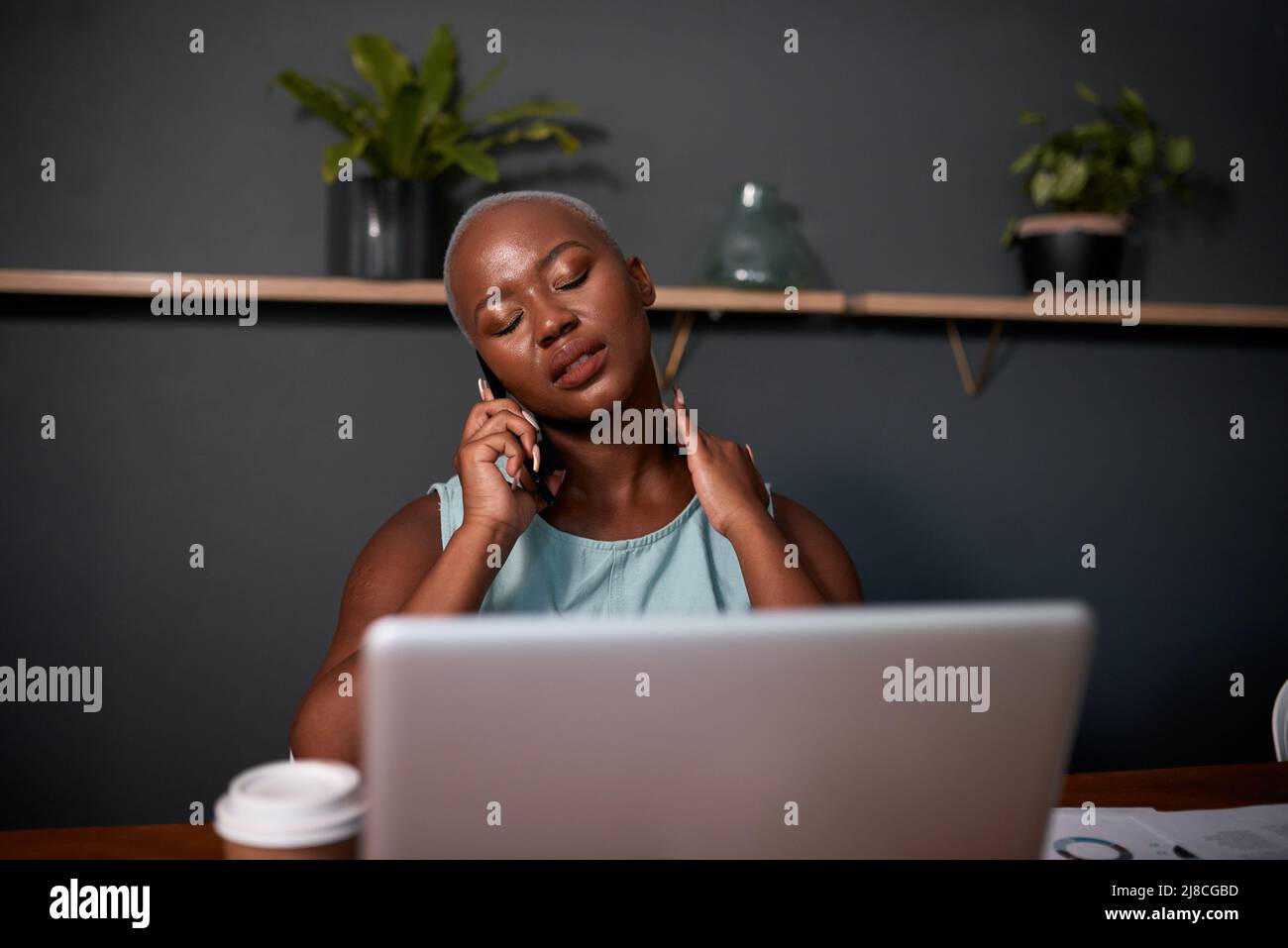 Una giovane donna nera prende una chiamata a tarda notte in ufficio Foto Stock
