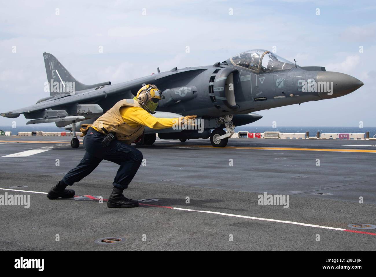 U.S. Navy Aviation Boatswains Mate 3rd Class Alissa Sanchez segnala un corpo marino AV-8B Harrier attaccato alla pecora nera dell'attacco marino Squadron 214, per lanciare dal ponte di volo della nave d'assalto anfibio classe Wasp USS Essex, 14 gennaio 2022 sul Mar Cinese Meridionale. Foto Stock
