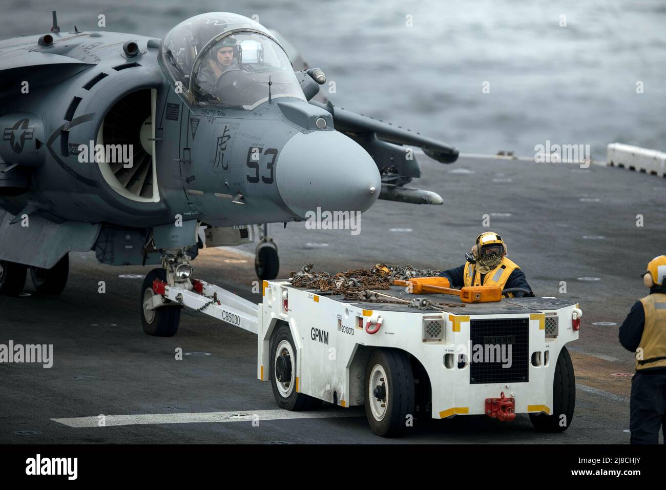 L'equipaggio del ponte di volo della Marina degli Stati Uniti traina un corpo della Marina AV-8B Harrier attaccato all'unità di spedizione marina 22nd, per lanciare la posizione sul ponte di volo della nave d'assalto anfibio di classe Wasp USS Kearsarge, 20 aprile 2022 sull'Oceano Atlantico. Foto Stock