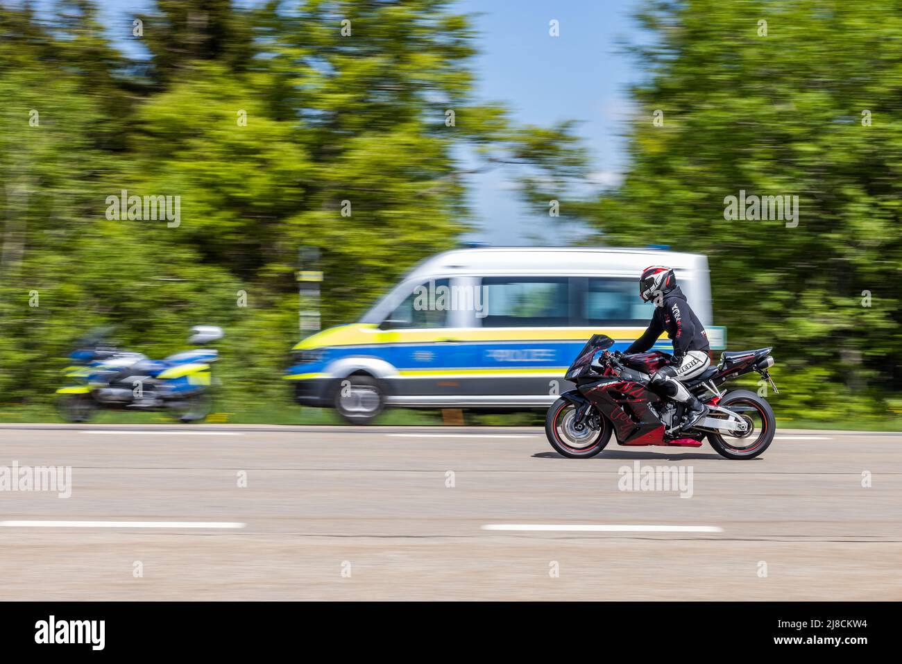 15 maggio 2022, Baden-Wuerttemberg, Pforzheim: Un motociclista passa davanti a un checkpoint della polizia. La sede della polizia di Pforzheim sta effettuando oggi un controllo motociclistico su larga scala sul B500 nel distretto di Freudenstadt. Foto: Philipp von Ditfurth/dpa Foto Stock
